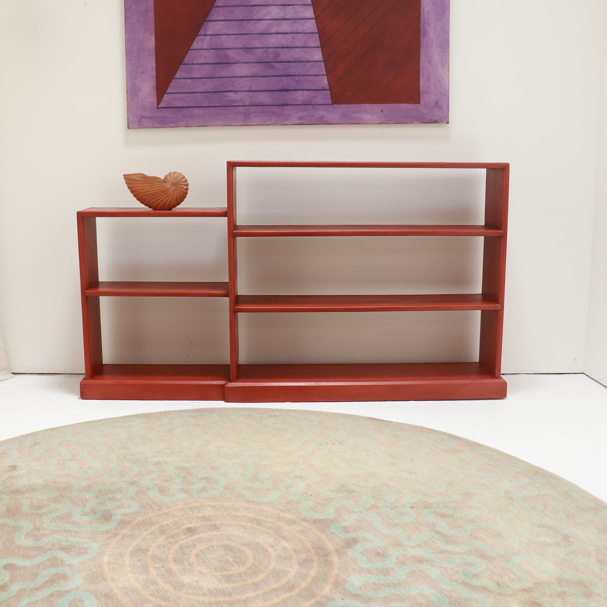 - Stepped red painted shelves displayed with a carved wooden shell