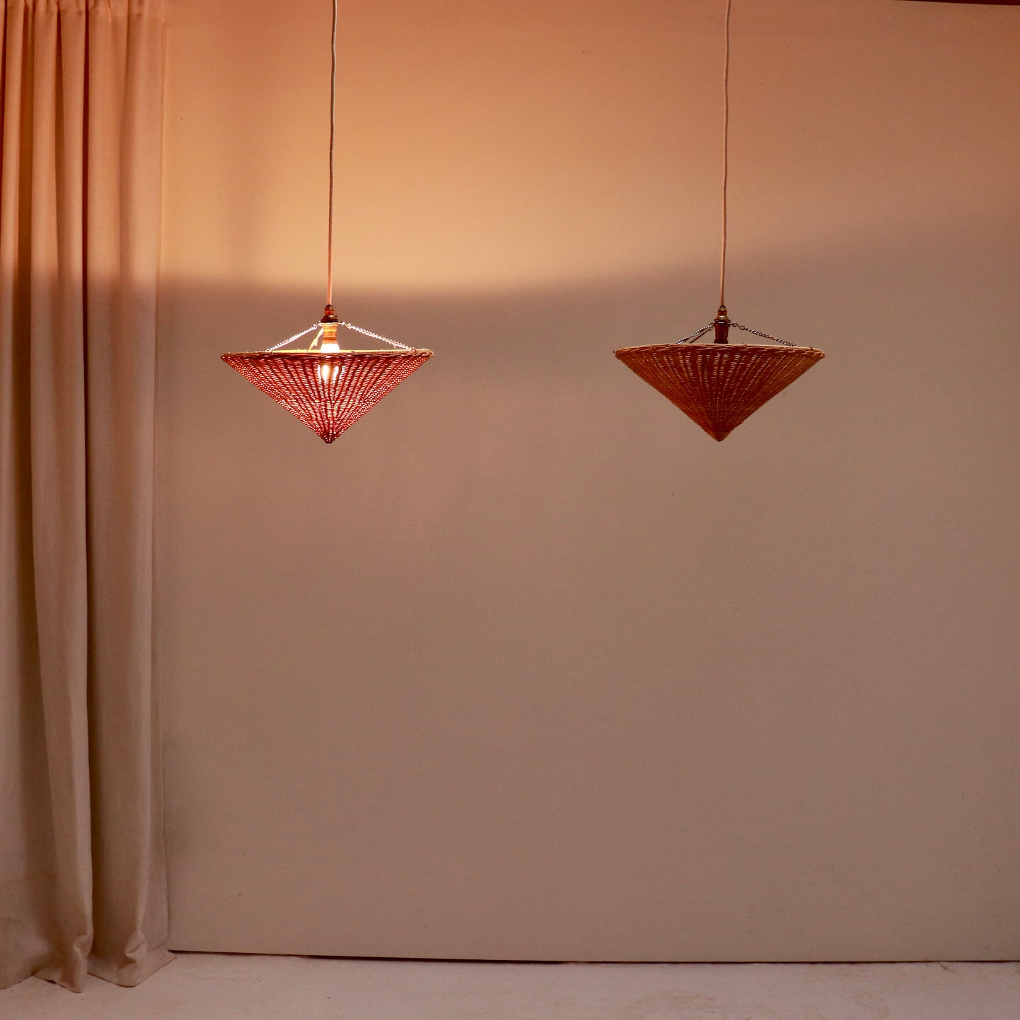 Rattan uplighter pendant light shown illuminated with warm glow