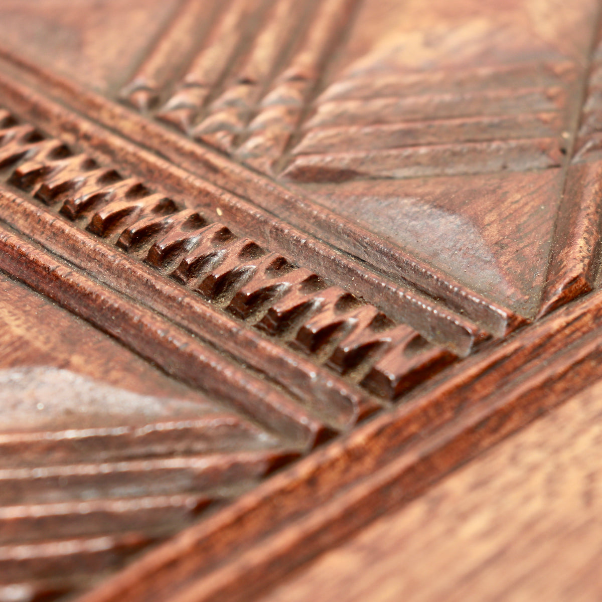 Close-up of notched borders and angular chip carving on the hardwood tabletop.