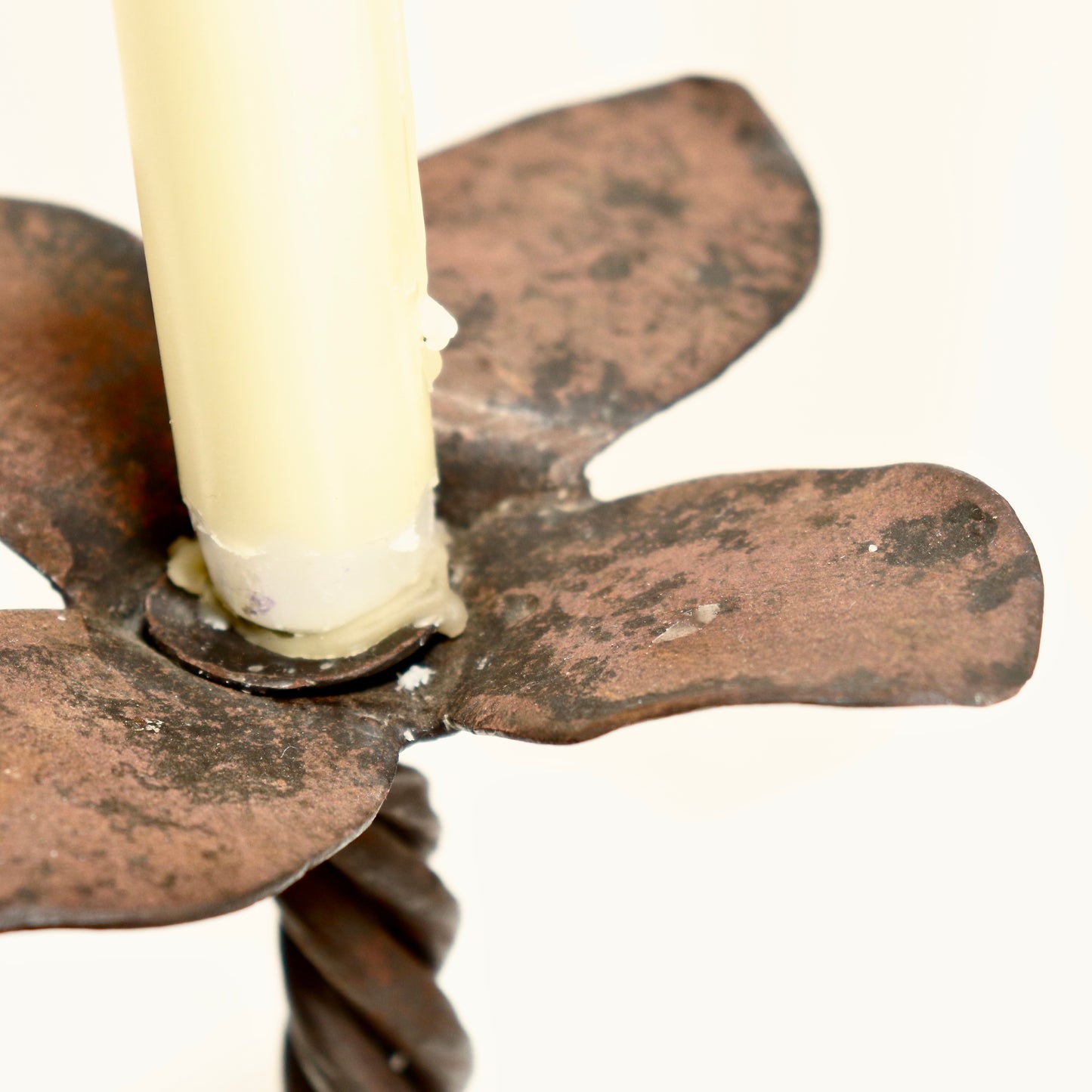 “Close-up patina and texture of artisan-forged iron candlestick”