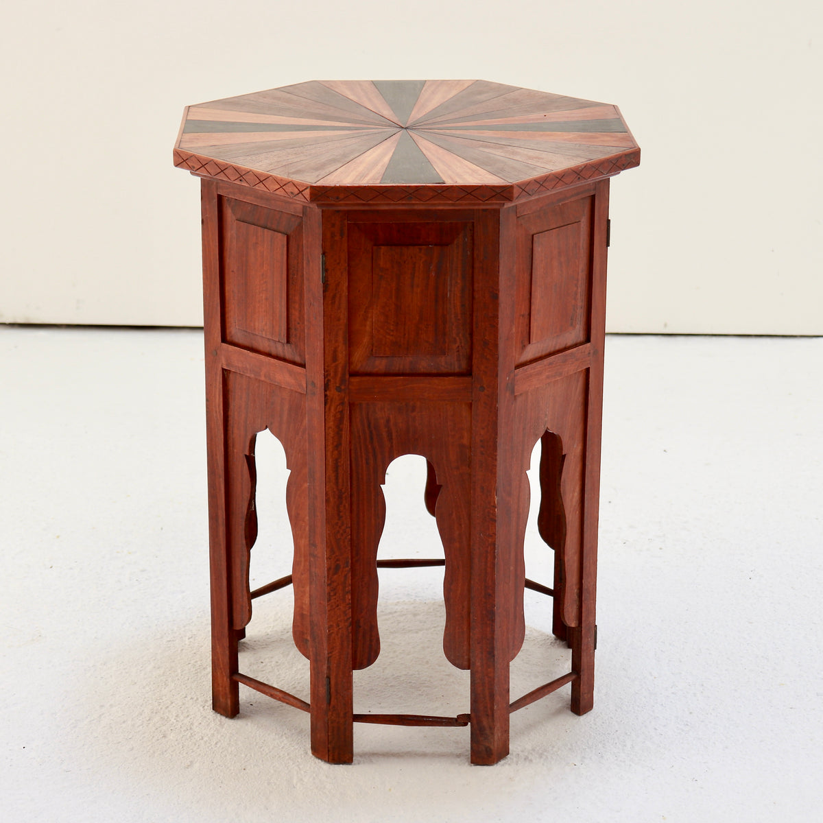 Full view of the octagonal side table showing its radiating wood top and arched panelled base.