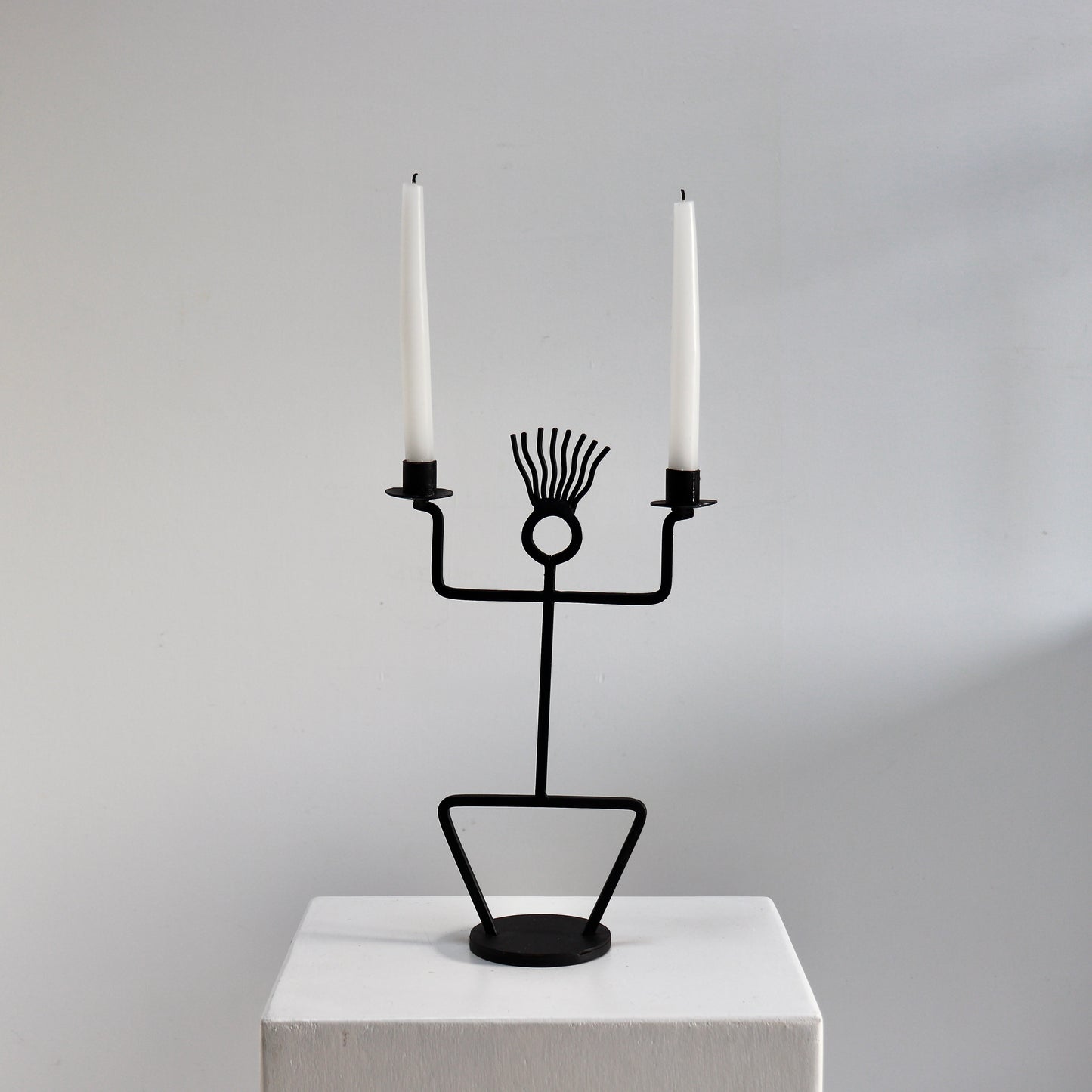 Figural wrought iron candle holder with twin arms and circular head detail