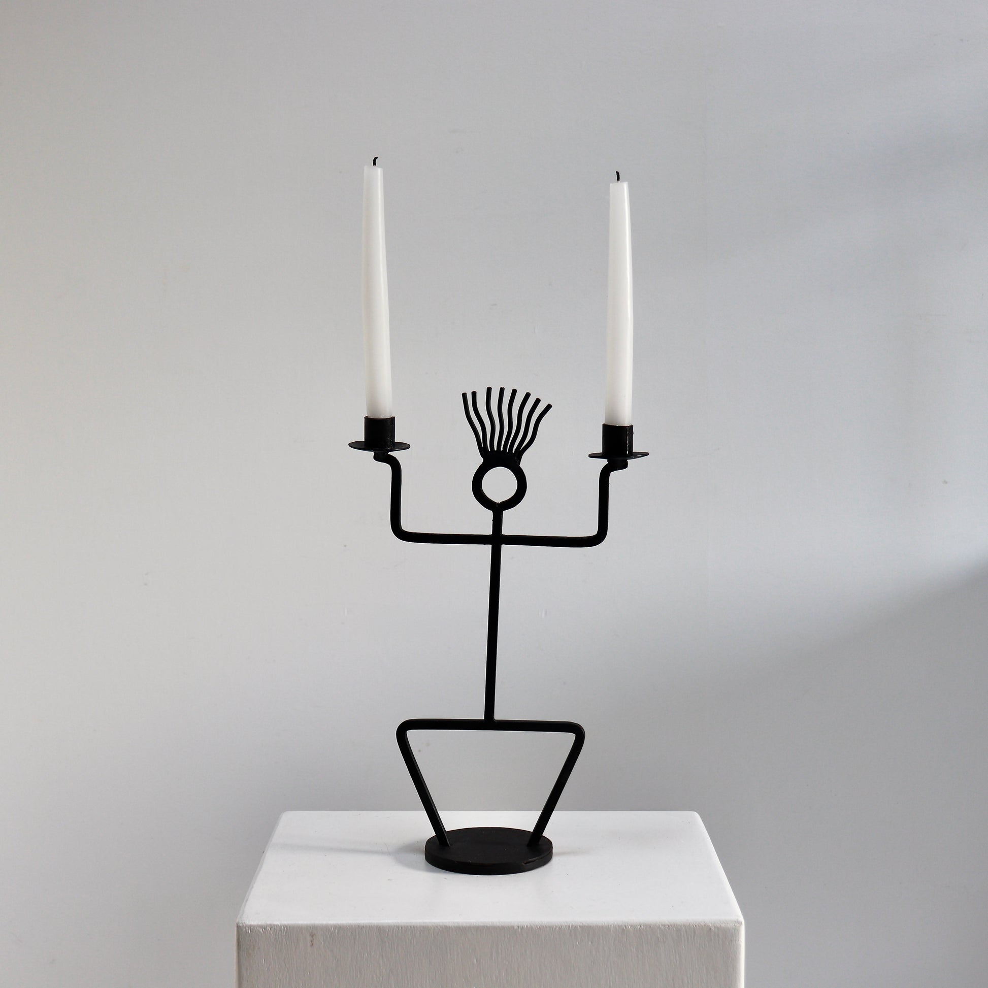 Figural wrought iron candle holder with twin arms and circular head detail