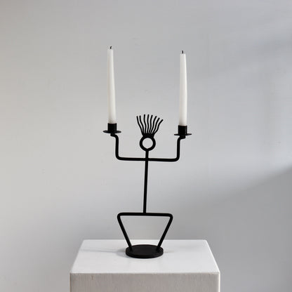 Figural wrought iron candle holder with twin arms and circular head detail
