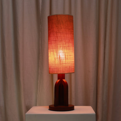 Oak table lamp illuminated with its tall fabric shade