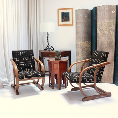 Pair of 1930s Heal’s bentwood armchairs upholstered in antique Malian mud cloth, arranged beside a wooden table in a furnished interior.