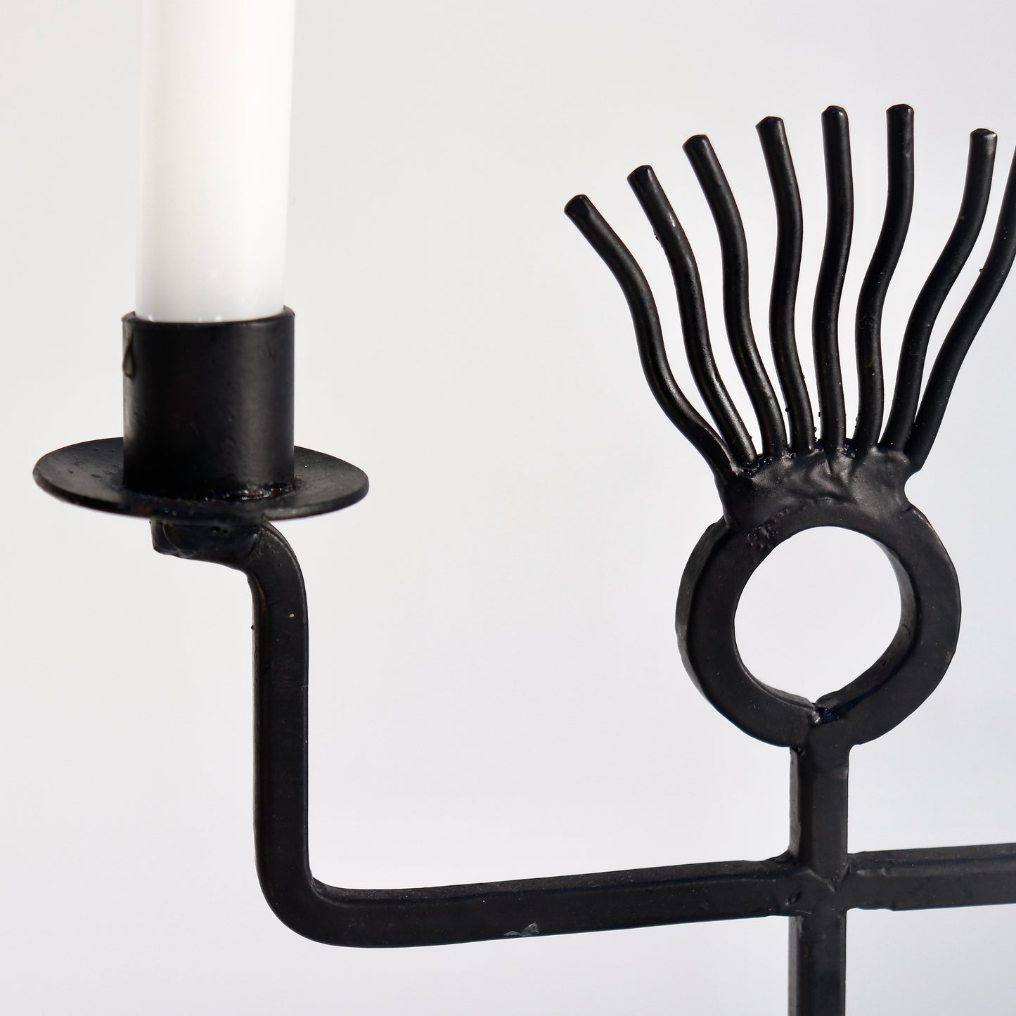 Close-up of iron rod figure candle holder arms and head