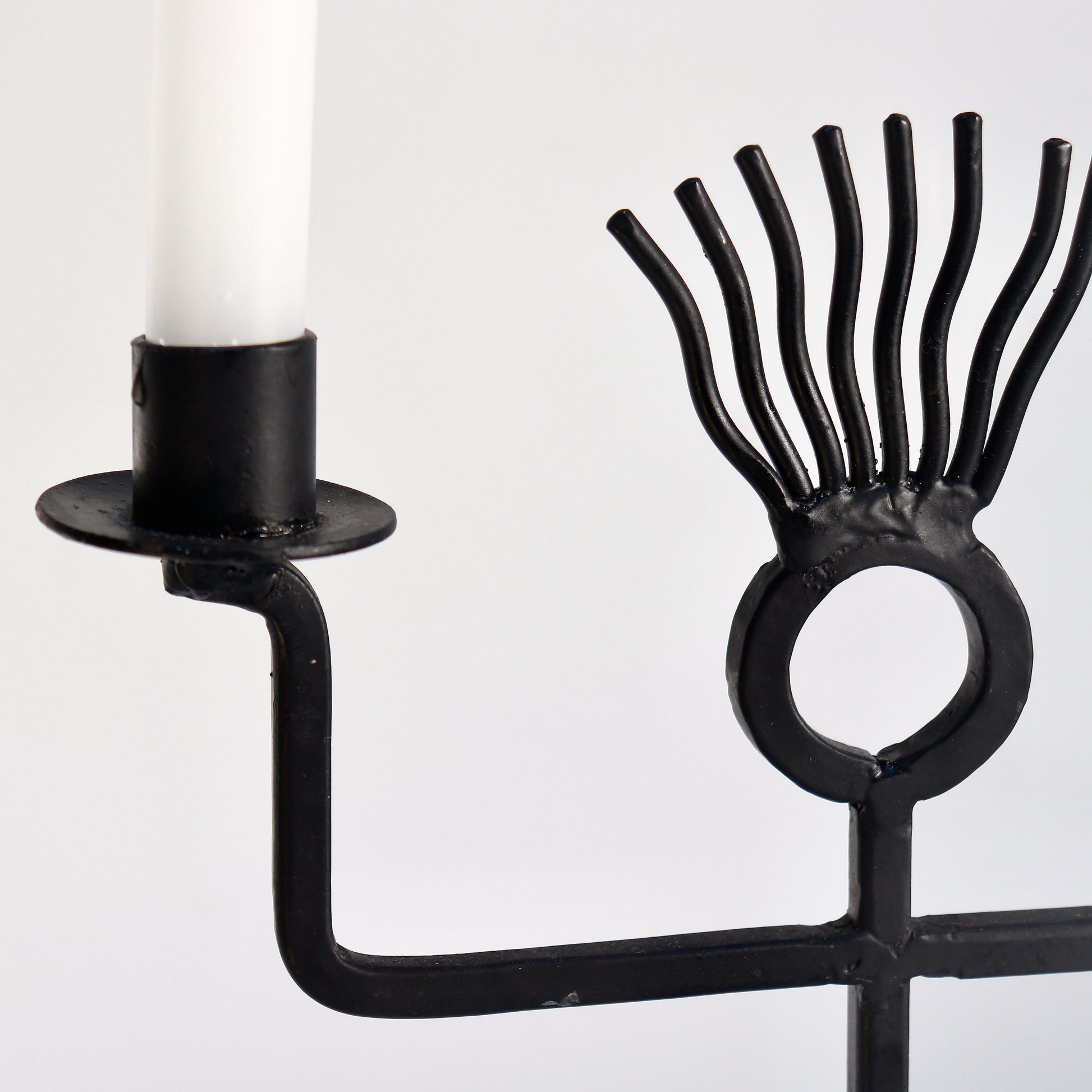 Close-up of iron rod figure candle holder arms and head