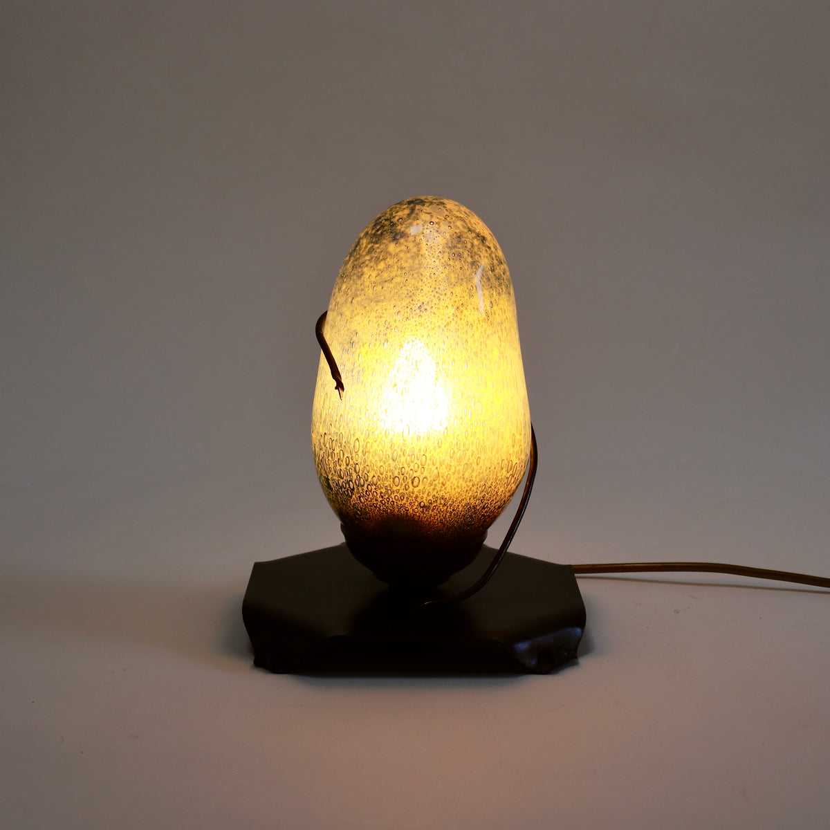 Bubble glass and copper table lamp illuminated with a warm golden glow