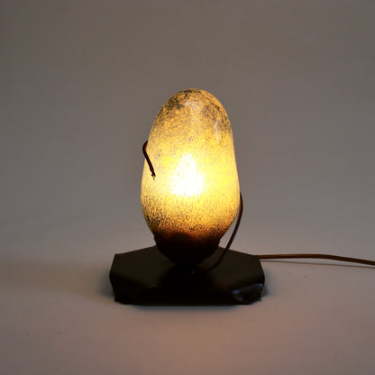Bubble glass and copper table lamp illuminated with a warm golden glow