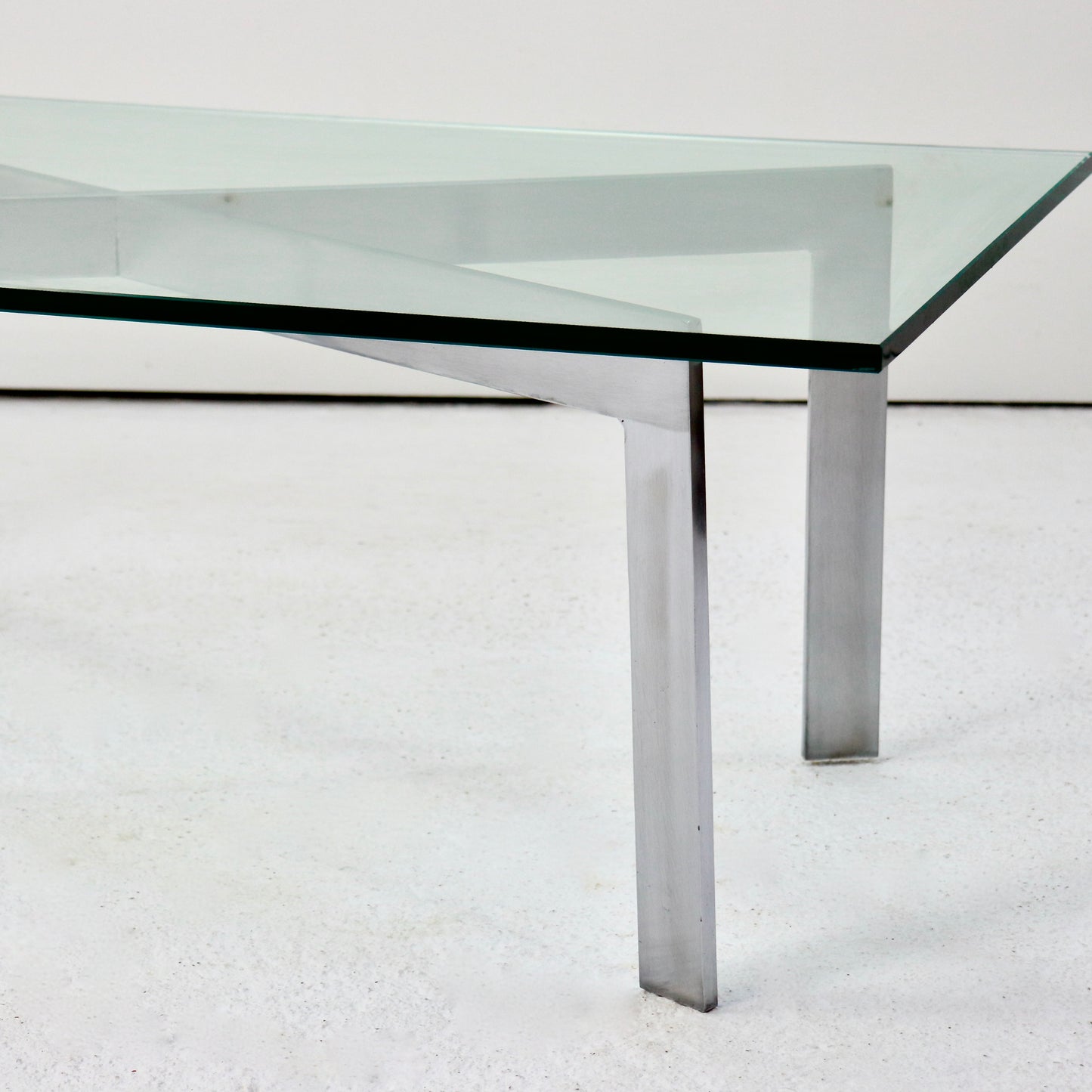 Side view of Barcelona-inspired glass and steel table