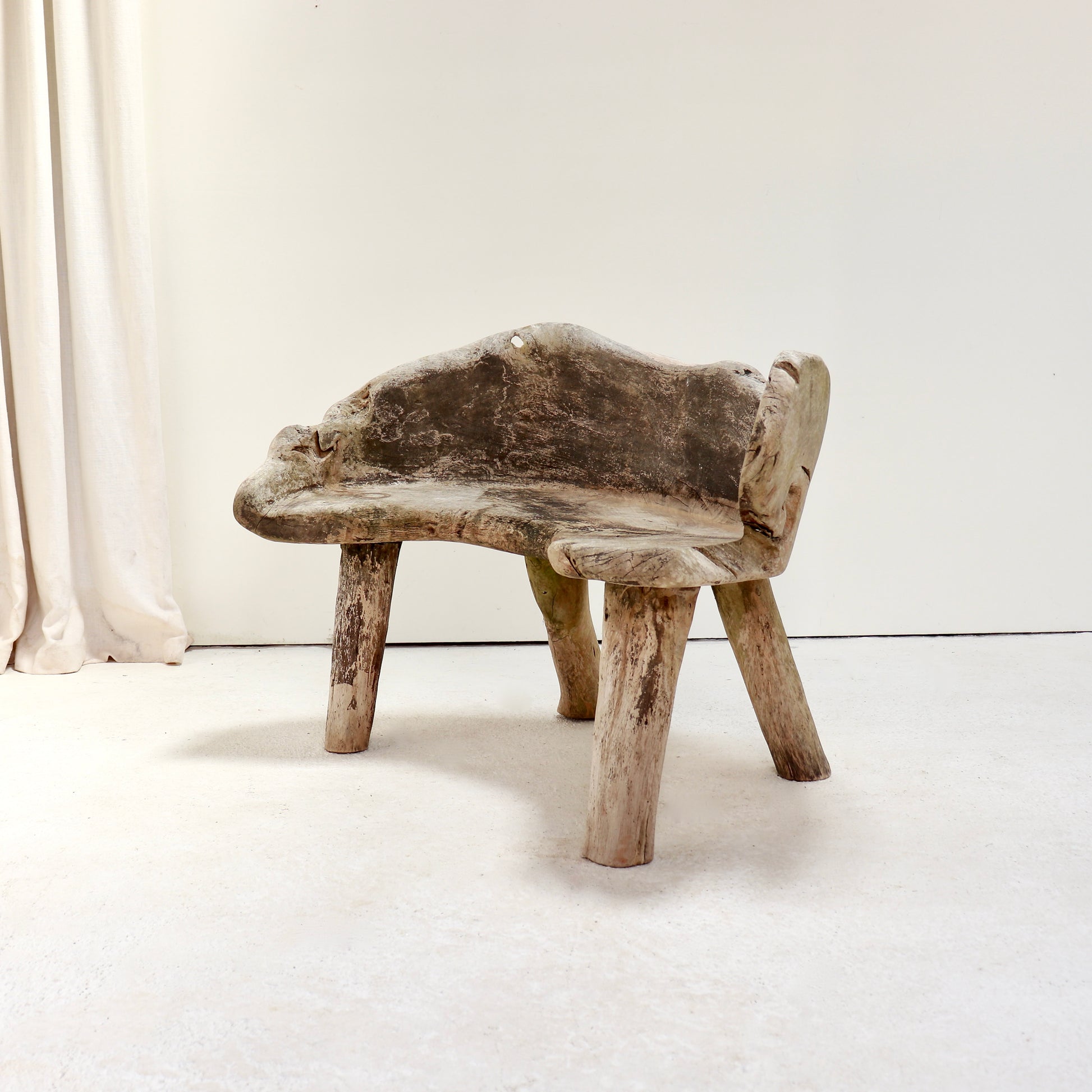 Three-quarter view of a sculptural hand-carved hardwood garden bench.