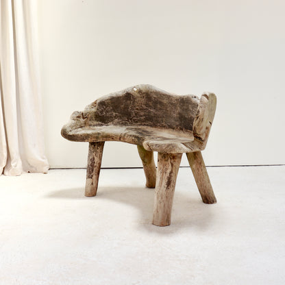 Three-quarter view of a sculptural hand-carved hardwood garden bench.
