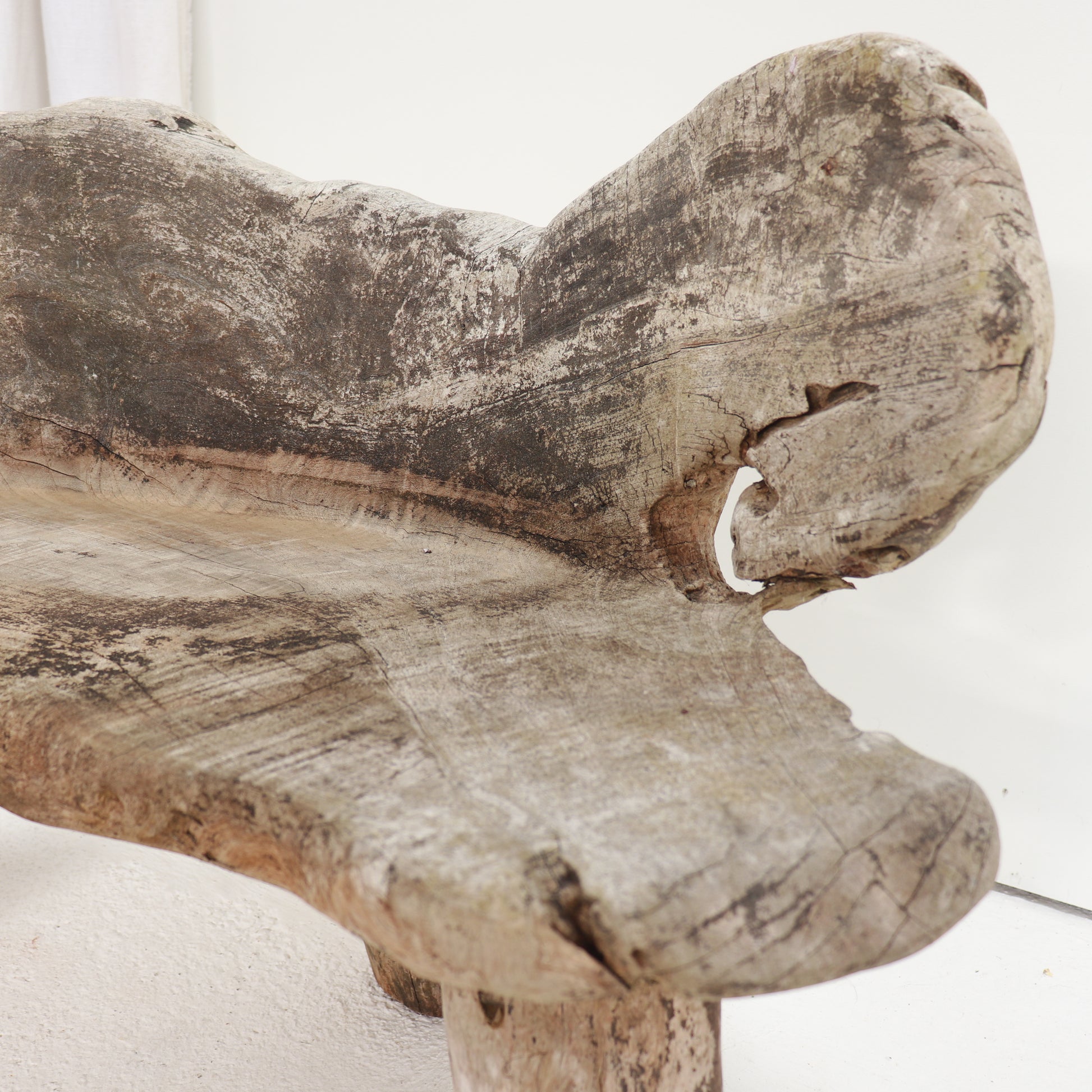 Close-up detail of the carved hardwood bench showing natural splits and weathered patina.