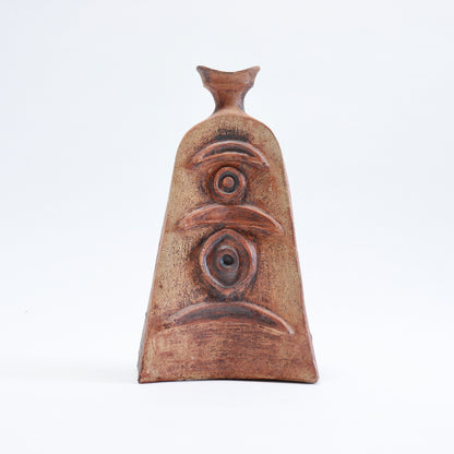 Front view of a sculptural Cornish pottery vessel with crescent shapes, concentric circles and an oval motif arranged vertically.