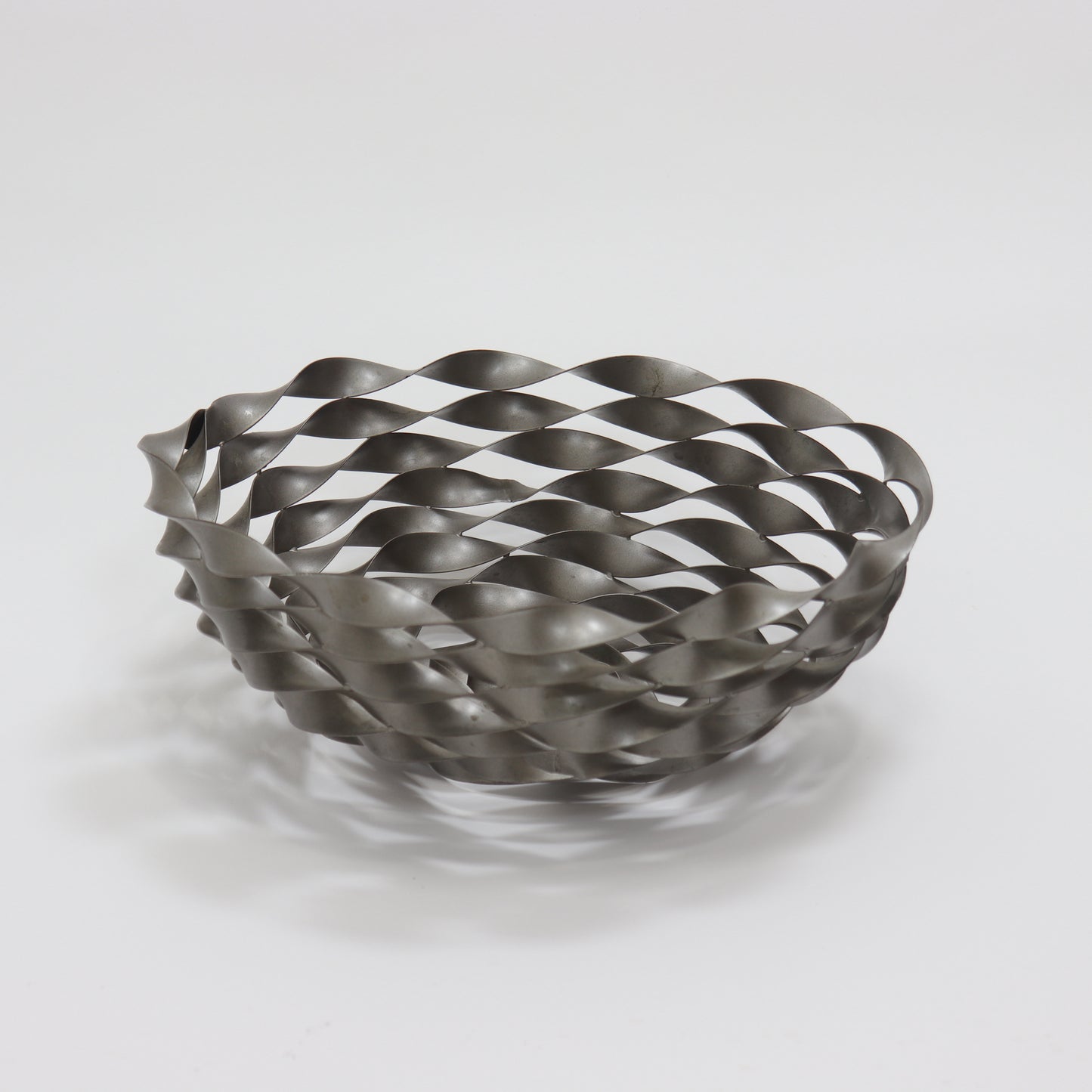 Sculptural twisted metal fruit bowl with interwoven ribbon lattice design
