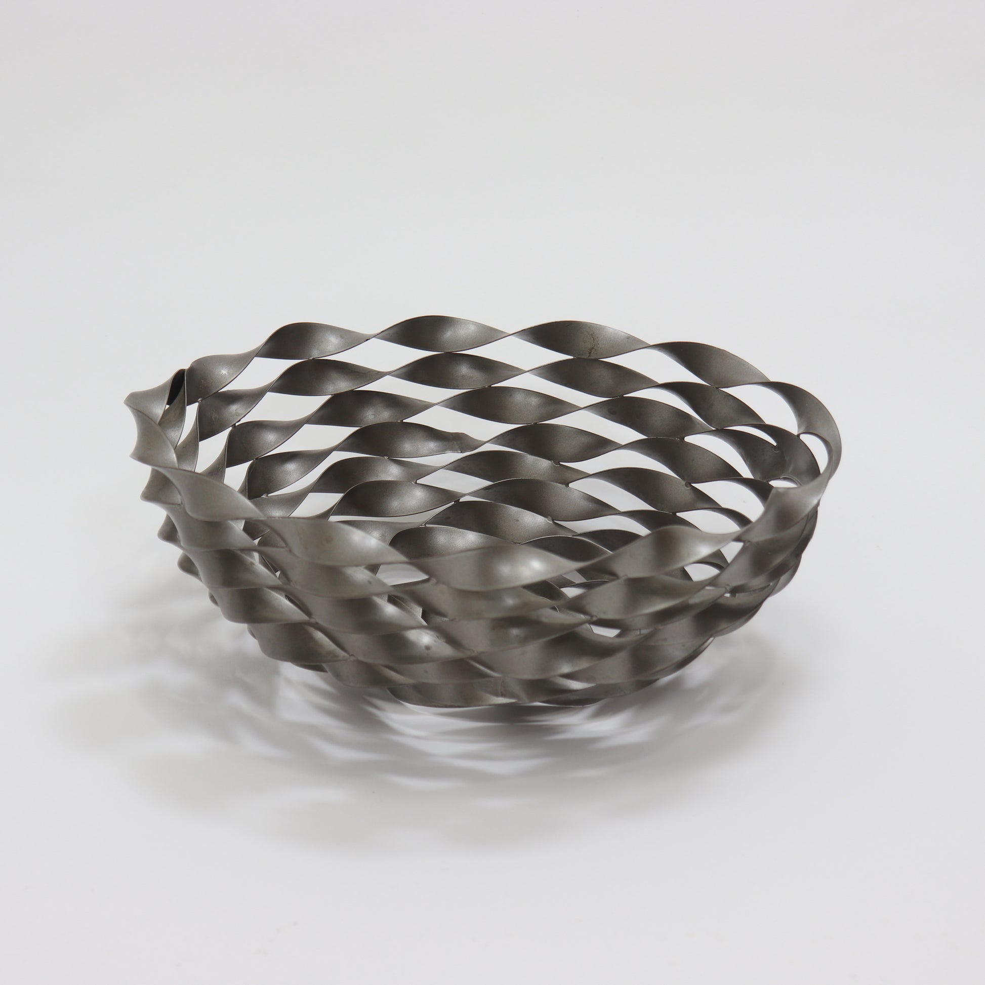 Sculptural twisted metal fruit bowl with interwoven ribbon lattice design