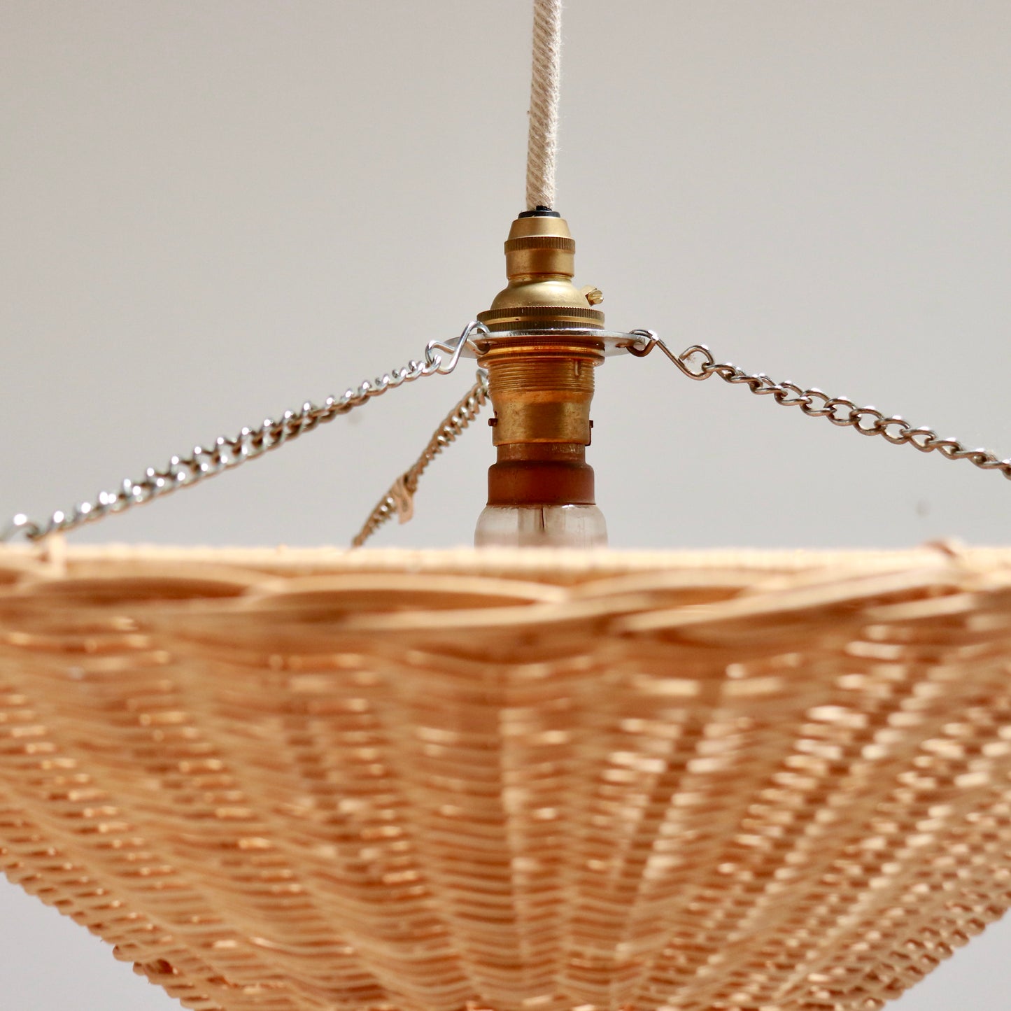 Detail of brass lampholder and chain supports on rattan pendant light