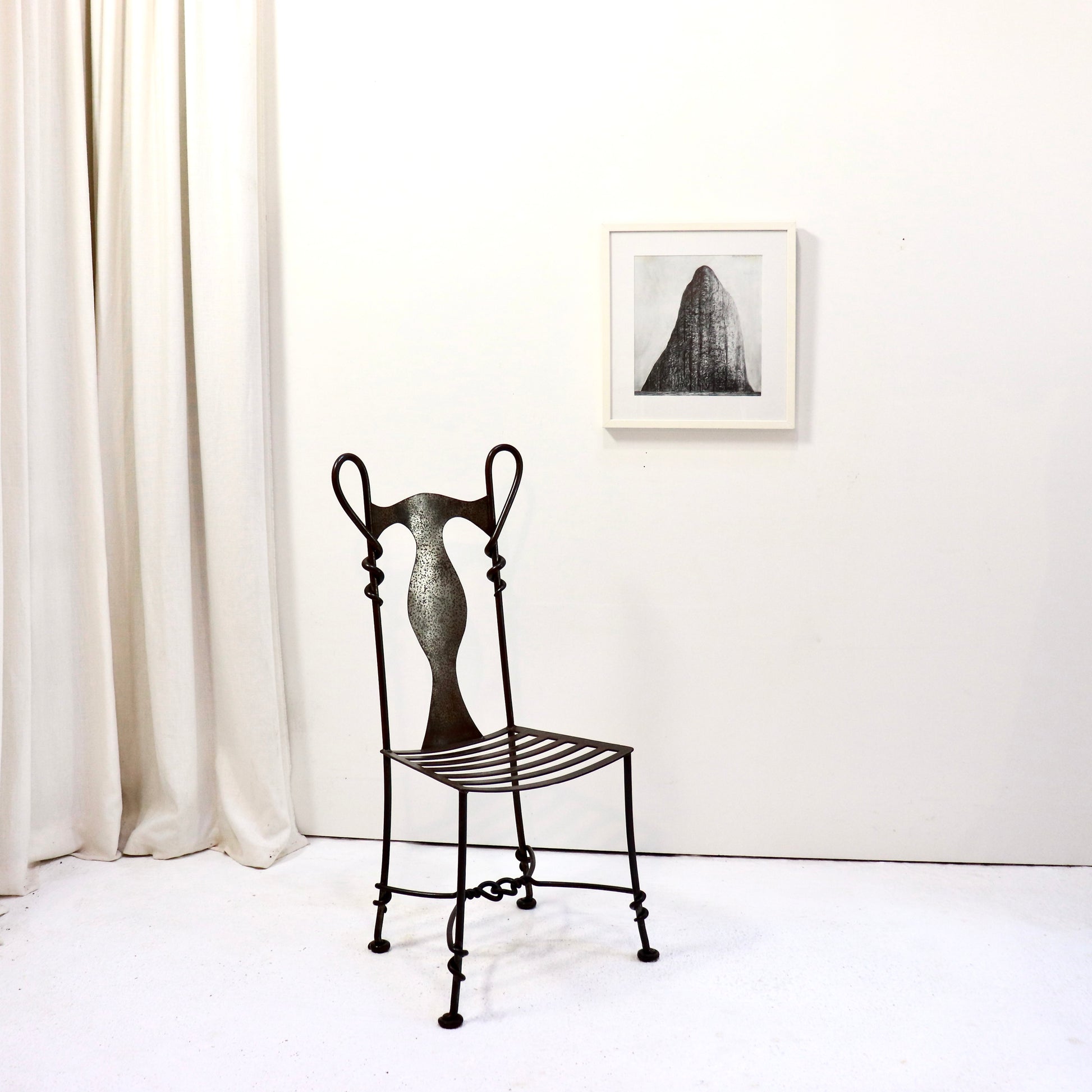 Installation view with wrought iron chair and artwork