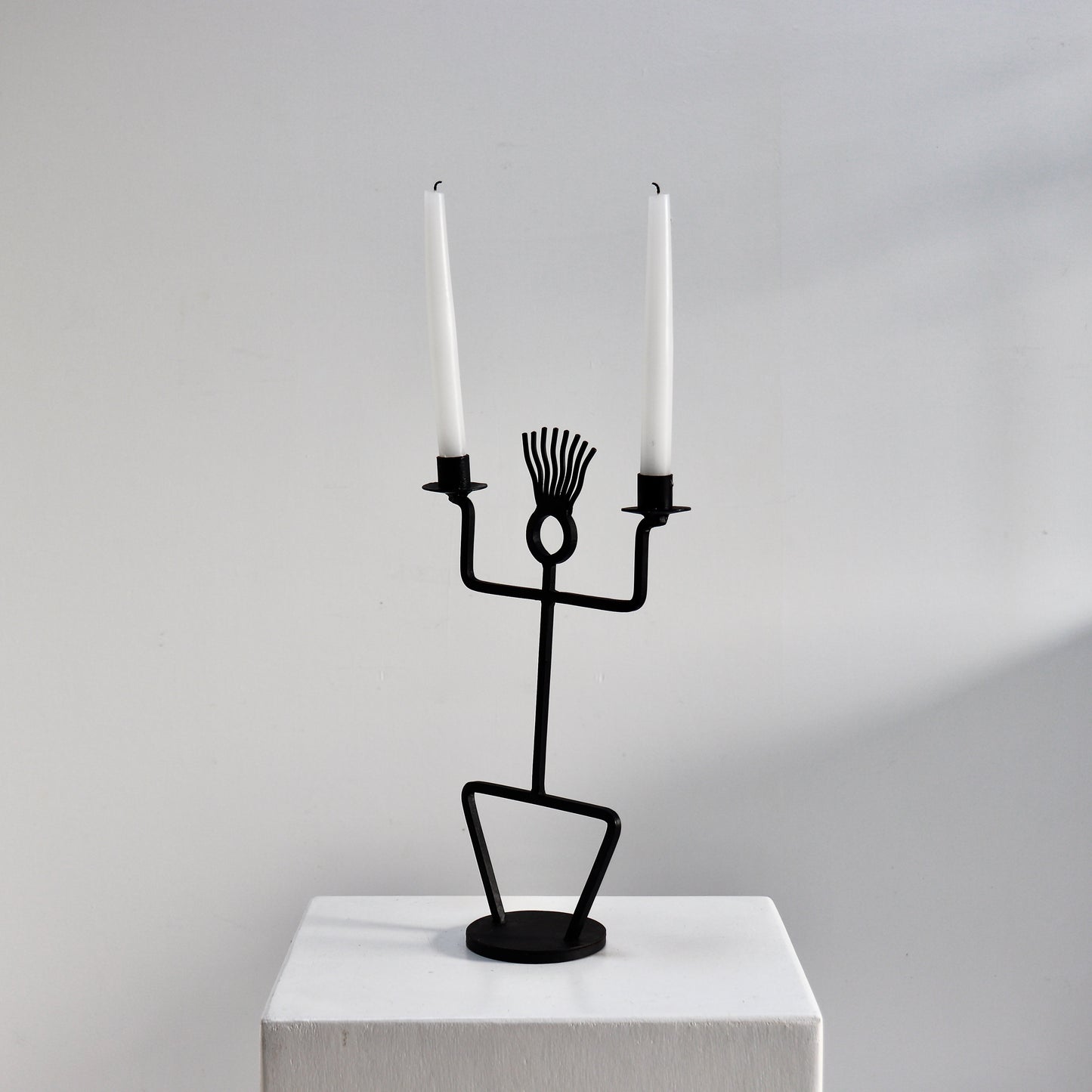 Sculptural black iron candle holder on round base