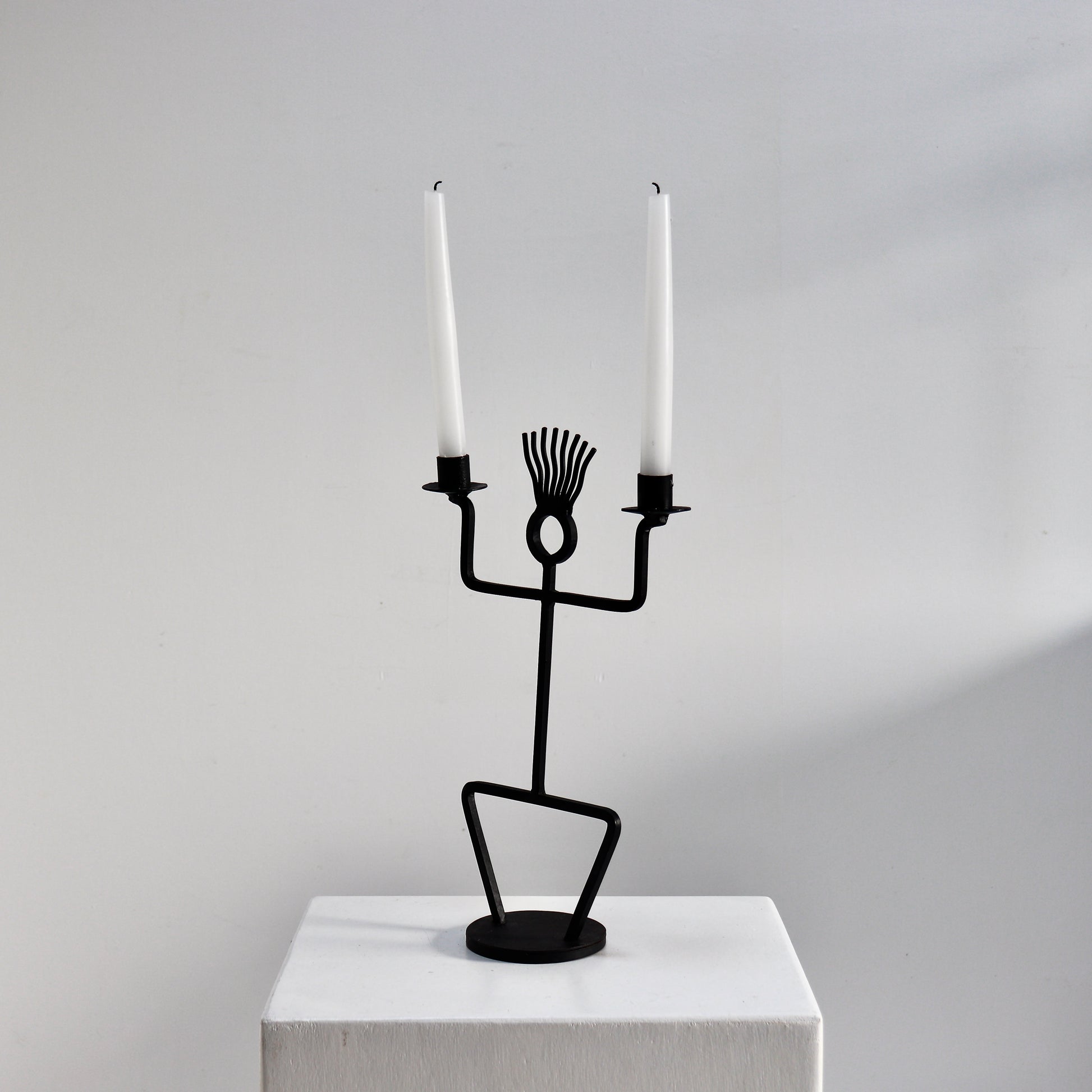 Sculptural black iron candle holder on round base