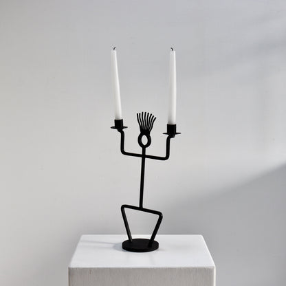 Sculptural black iron candle holder on round base