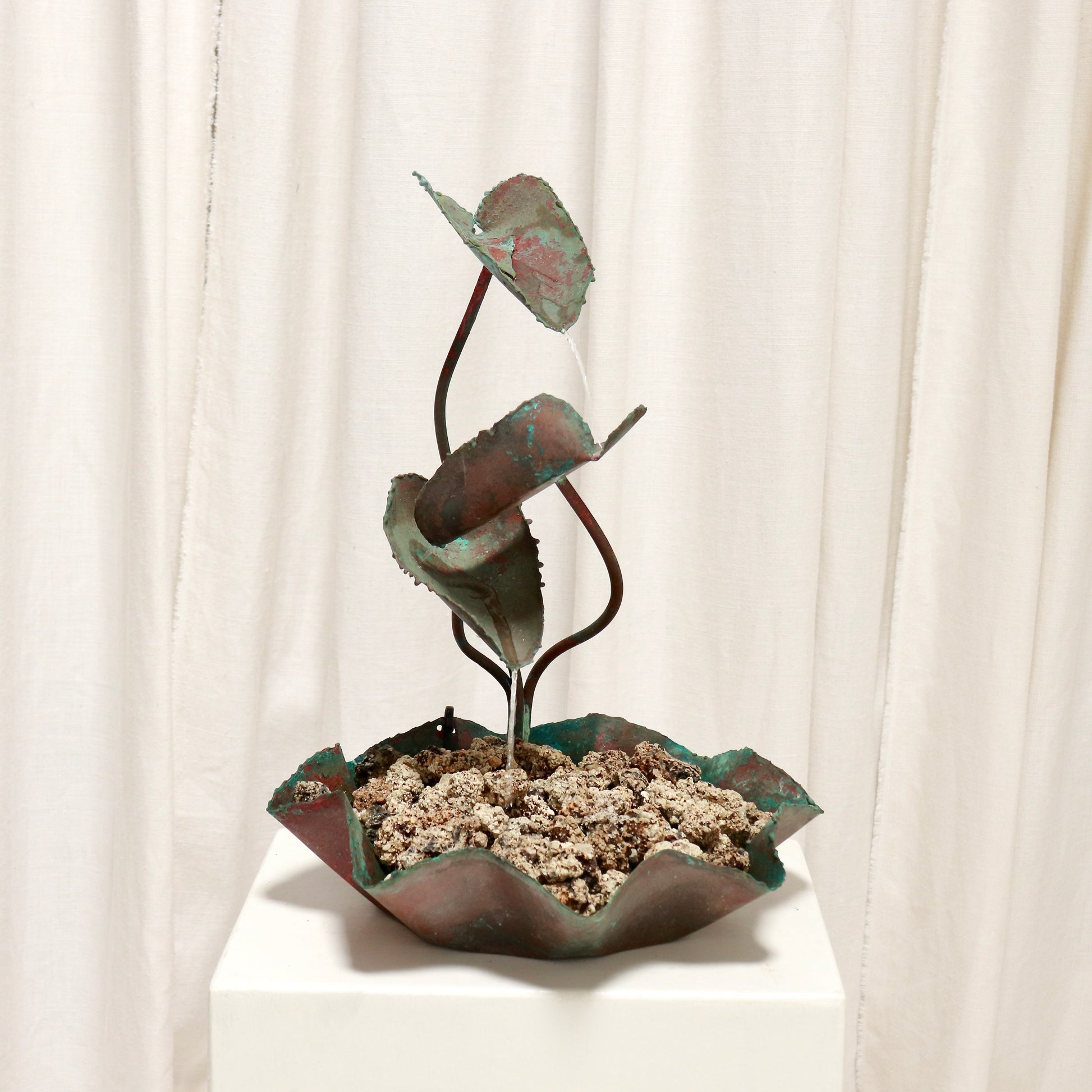 Vintage copper leaf table fountain with verdigris on white plinth.