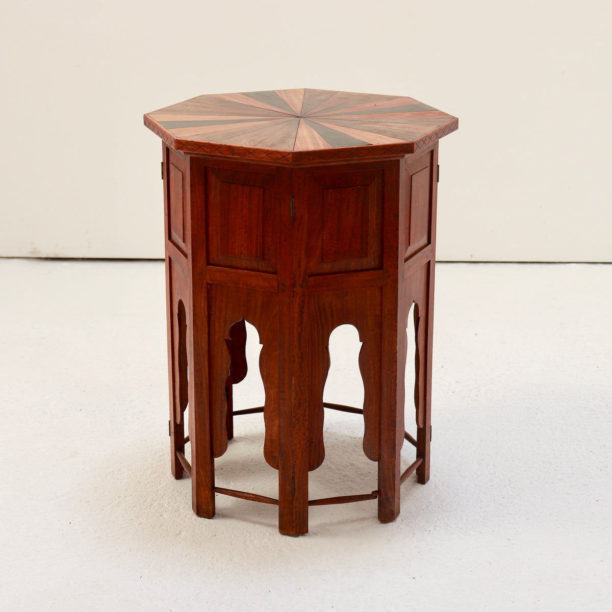Angled view of the folding wooden side table showing its hinged panels and shaped arches.