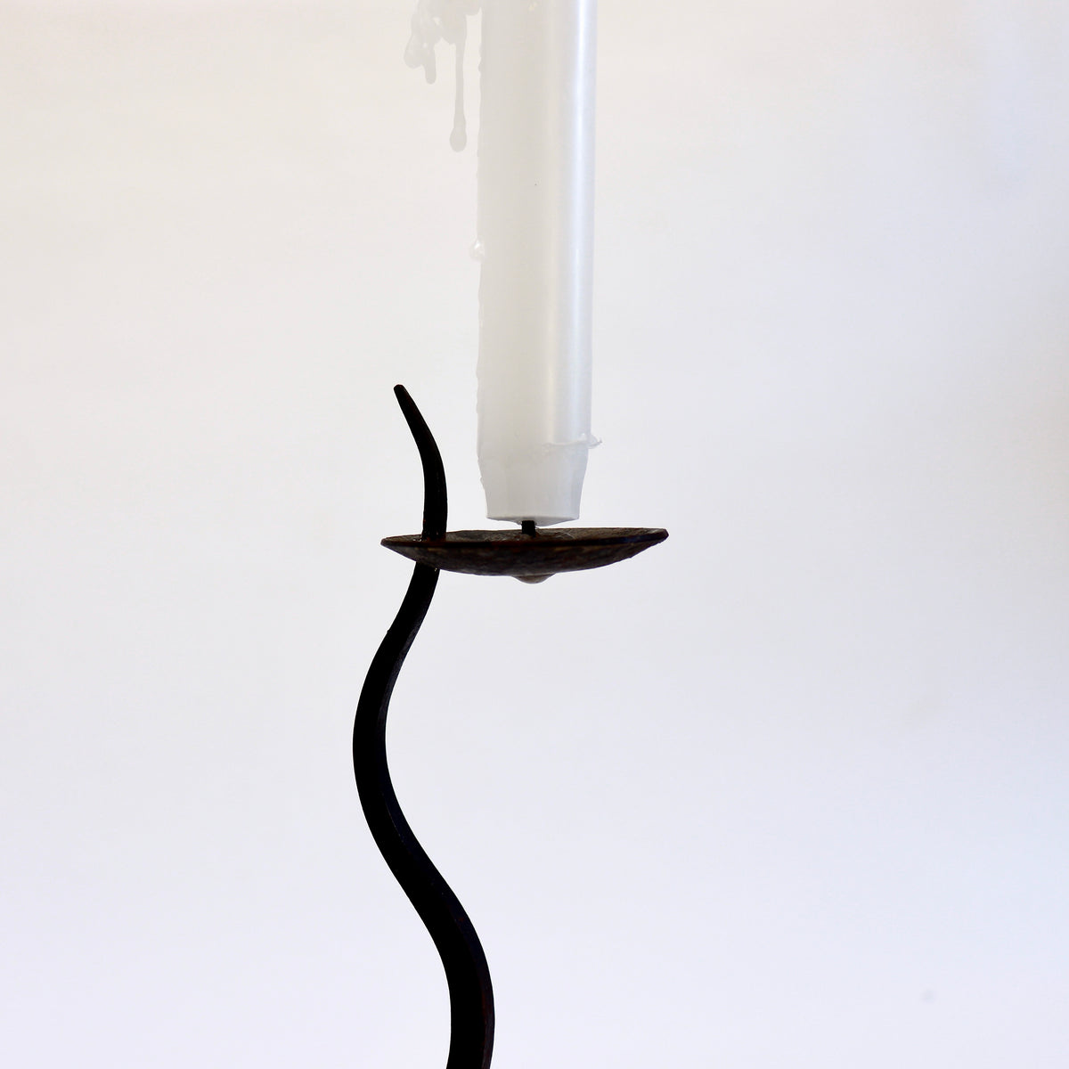 Close-up of the iron candle dish with central pricket, old wax residue and tapered stem tip.