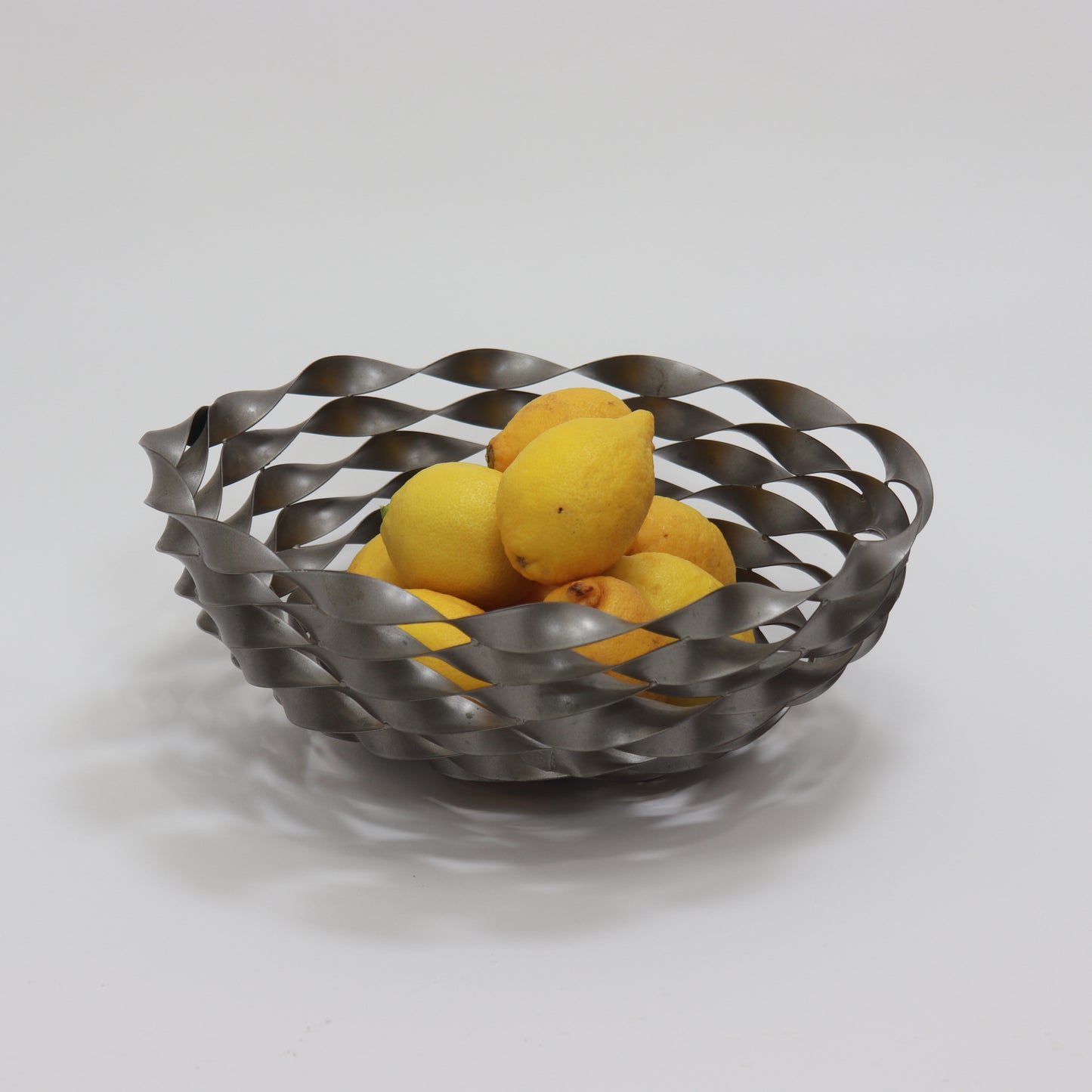 Vintage twisted steel bowl shown with lemons demonstrating scale