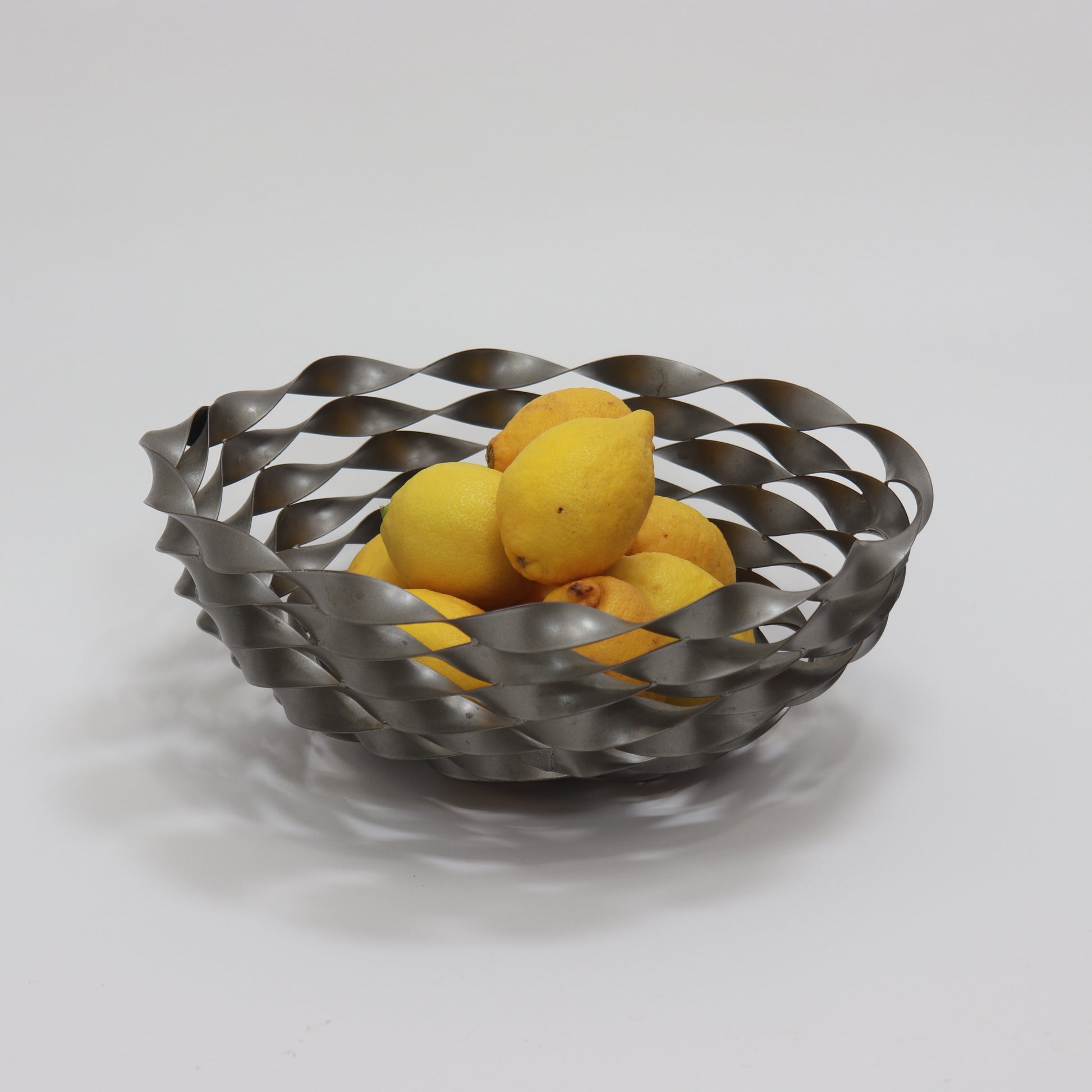 Vintage twisted steel bowl shown with lemons demonstrating scale