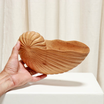 Hand holding the carved wood shell bowl to show its scale