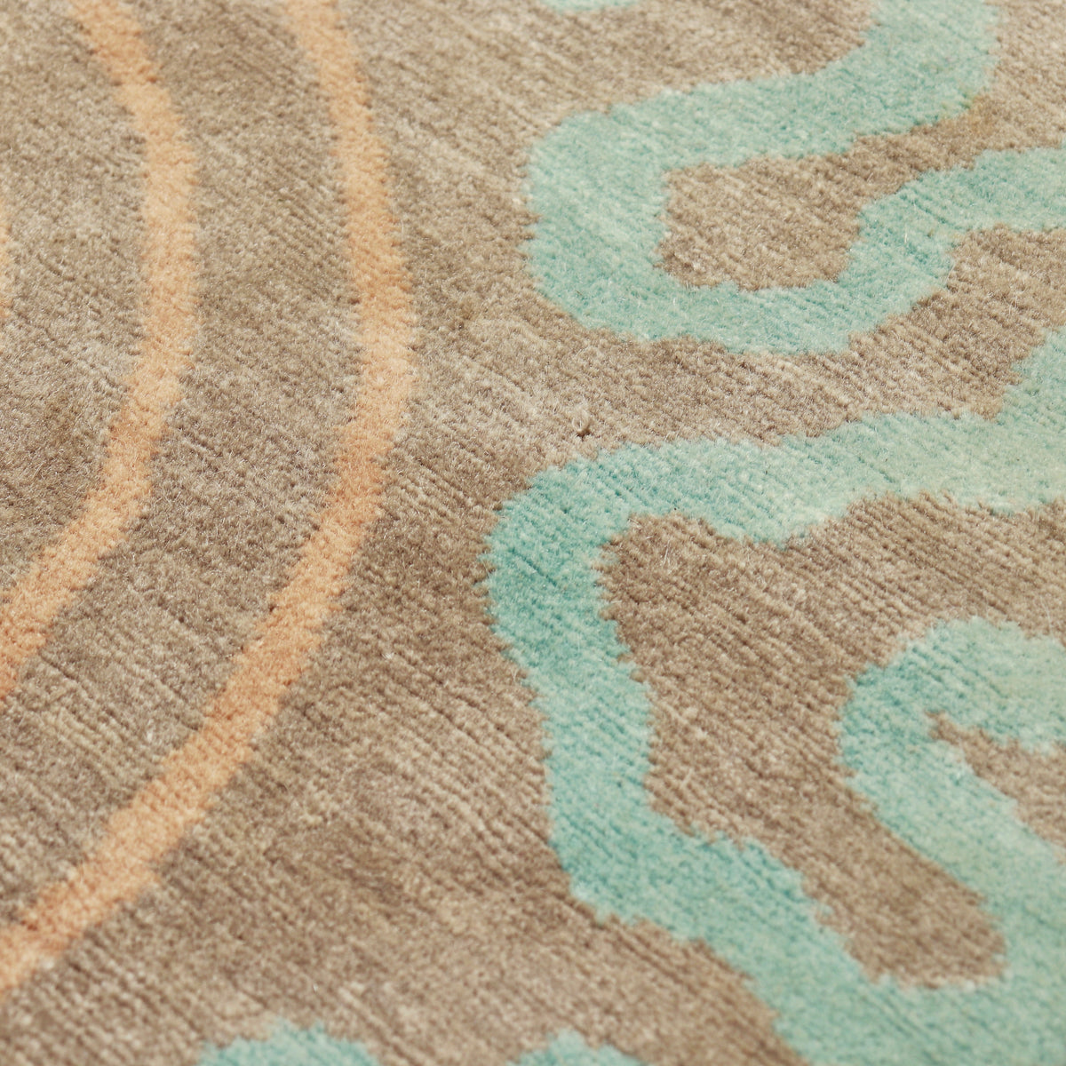 Close-up of the short wool pile with aqua squiggles, peach lines and small surface marks.
