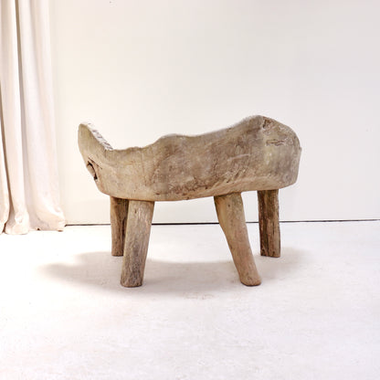 Rear view of primitive carved hardwood bench showing sculpted organic form.
