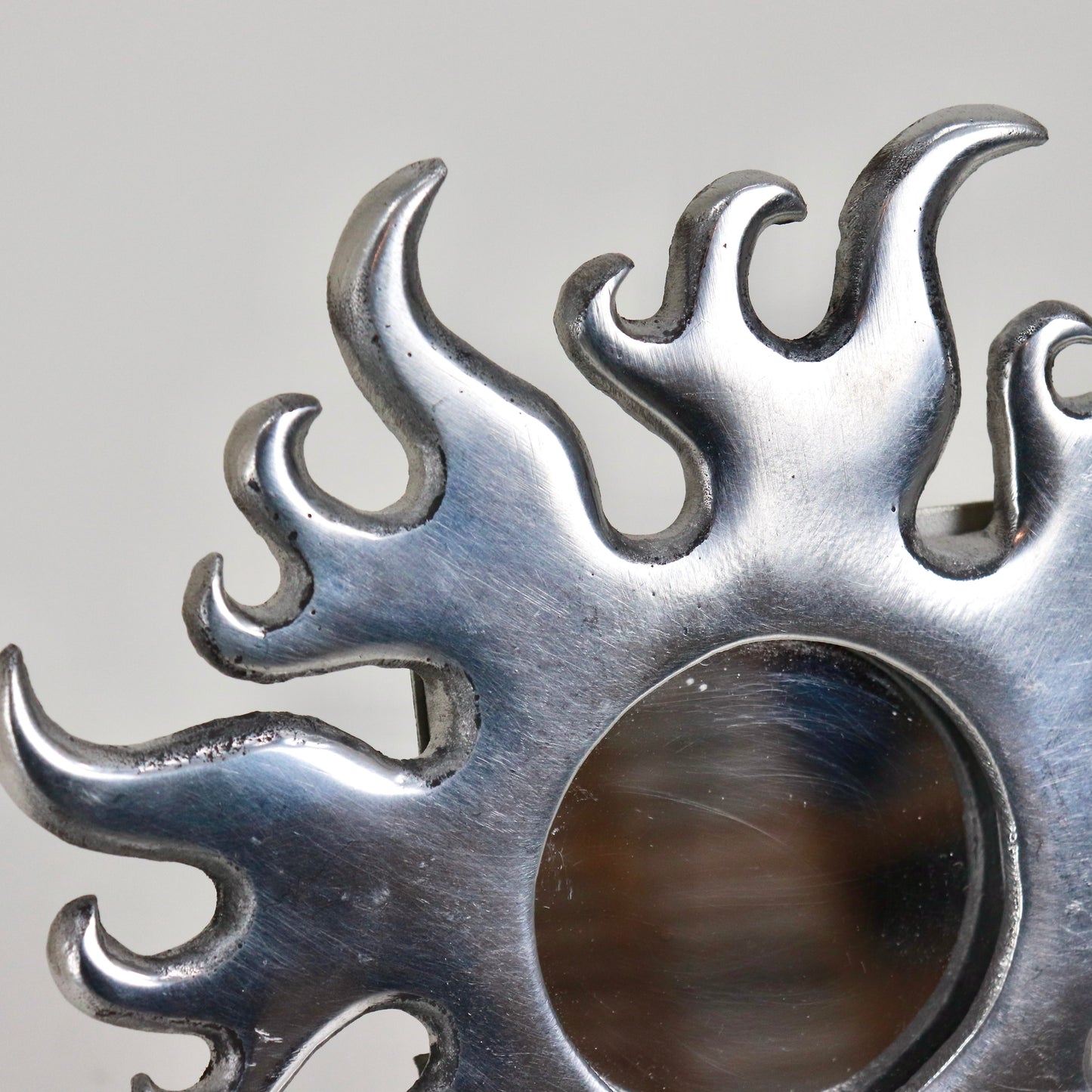 Detail of curling flame edges on cast aluminium mirror frame