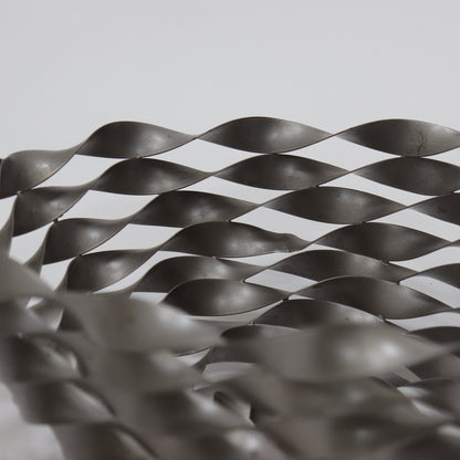 Close-up of woven steel ribbon structure with industrial finish