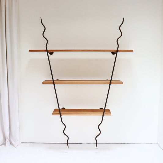 Sculptural wrought-iron wall shelves with three timber boards against a white wall.