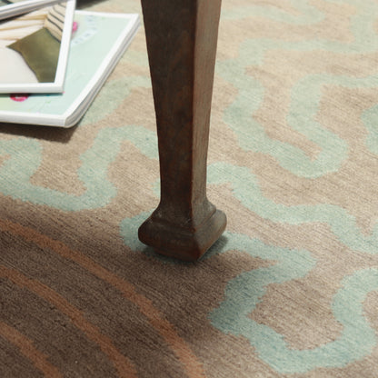Detail of the patterned wool rug beneath a wooden chair leg, with magazines nearby.