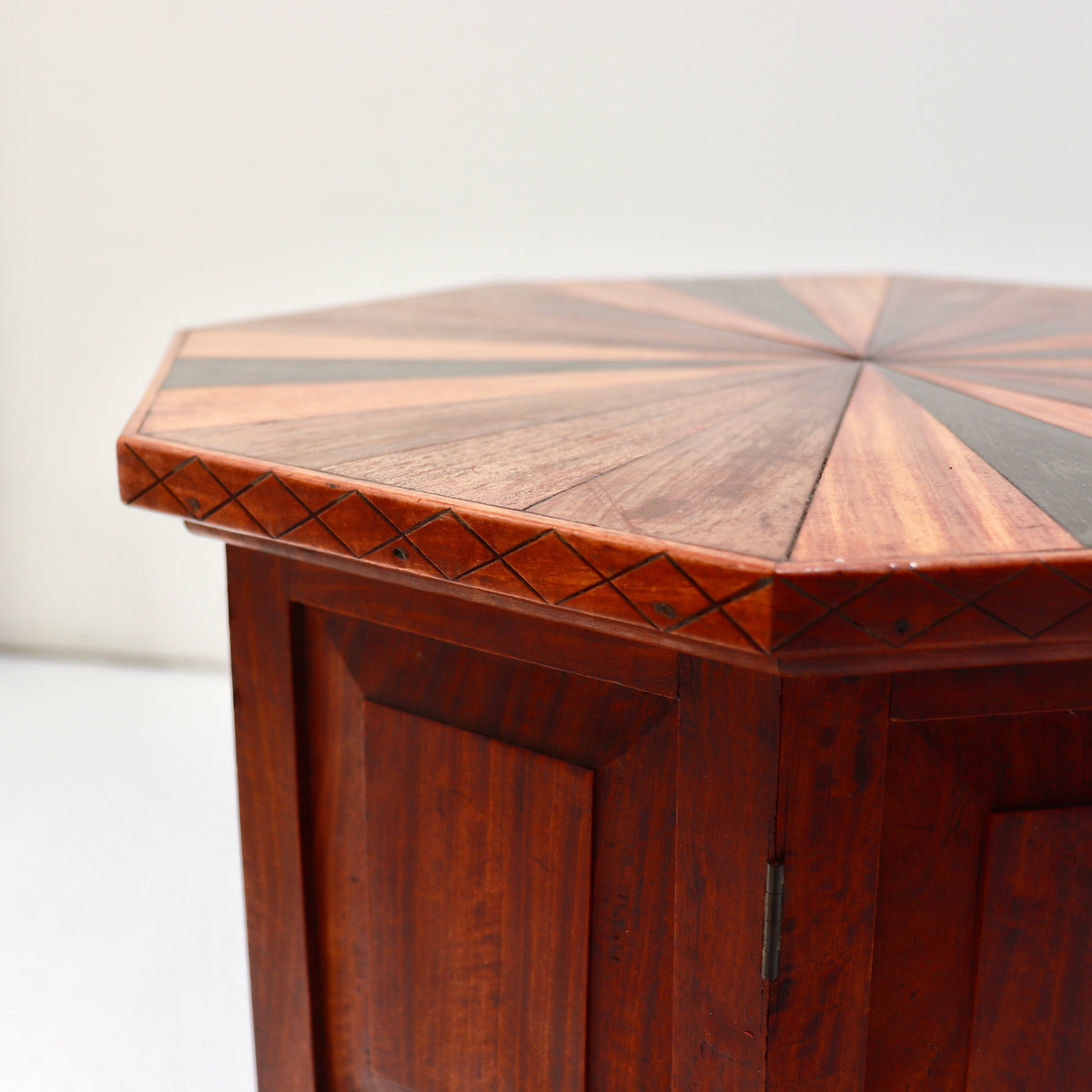 Detail of the tabletop’s incised diamond border, contrasting wood segments and base hinge.