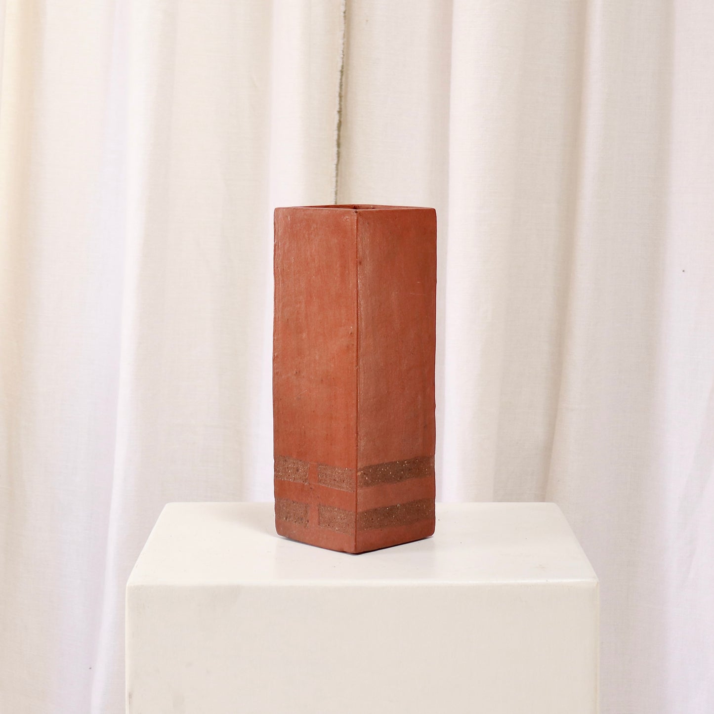 Three-quarter rear view showing banded base detail on square terracotta vase.