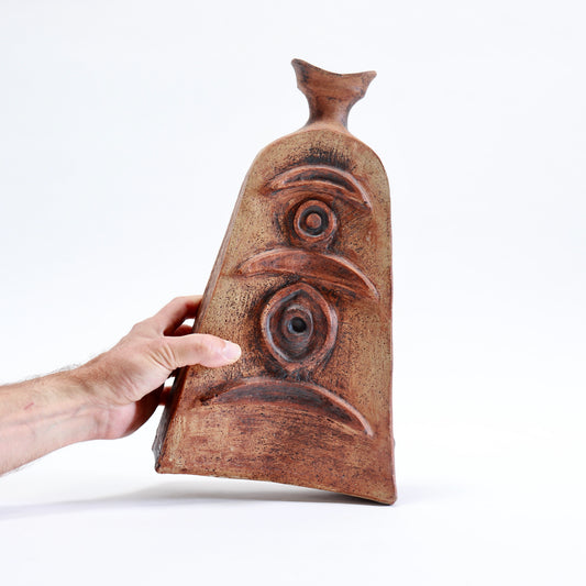 Hand holding a 35 cm tall Cornish pottery vessel to show its scale and sculptural relief decoration.