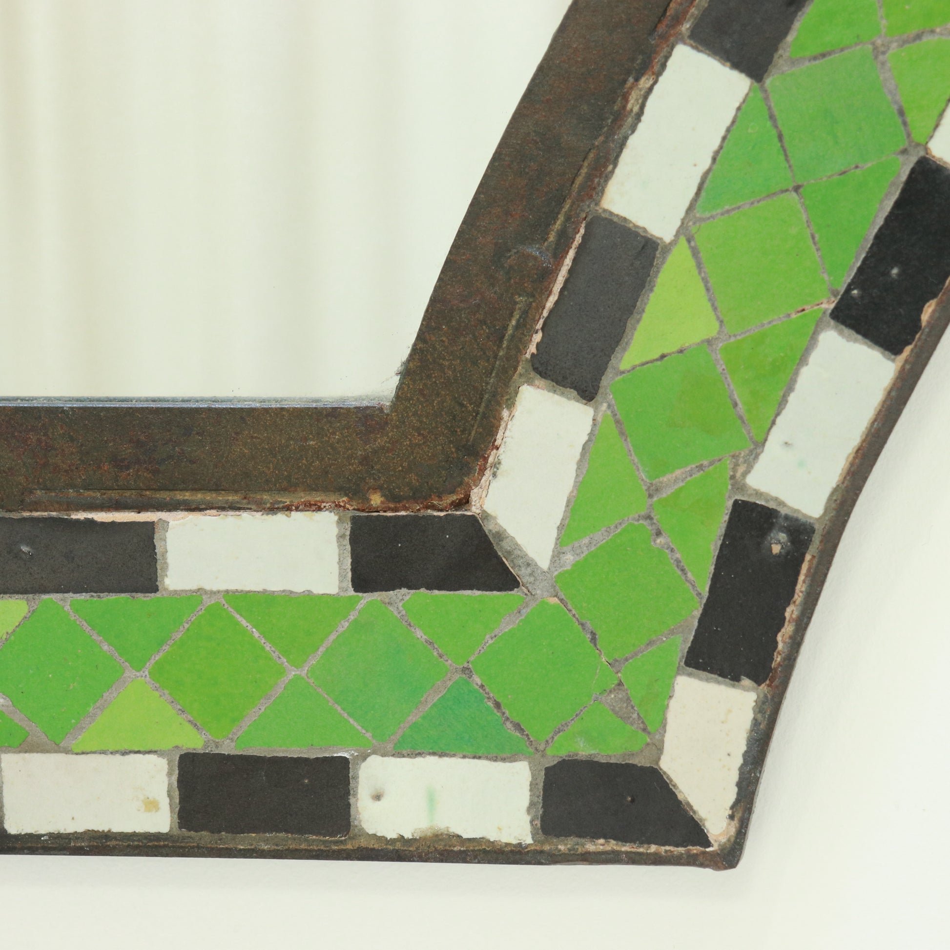 Close-up of green and white ceramic tesserae in wrought iron frame
