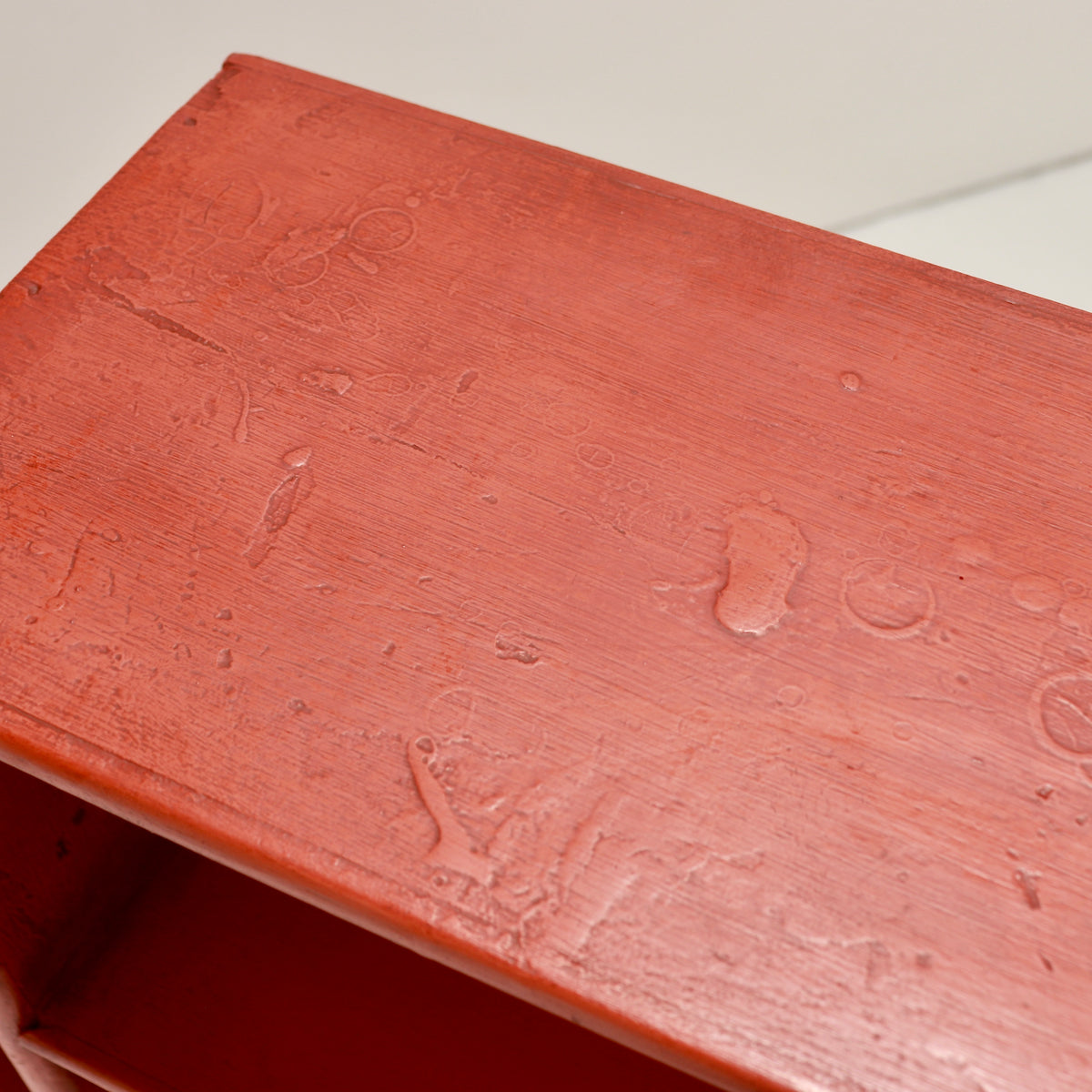 Close-up of the textured red paint with brush marks and surface irregularities
