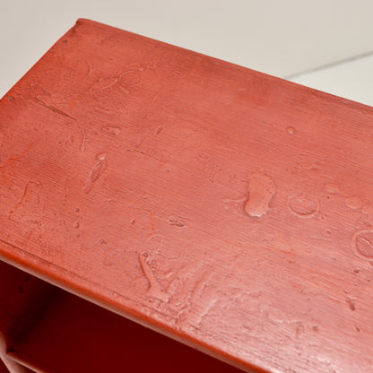Close-up of the textured red paint with brush marks and surface irregularities
