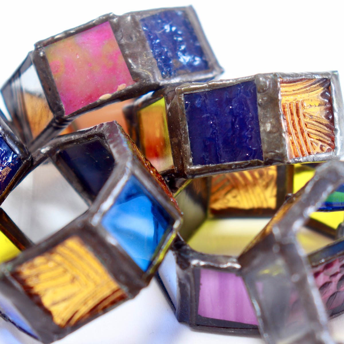 Detail of blue, amber and iridescent glass within soldered napkin rings