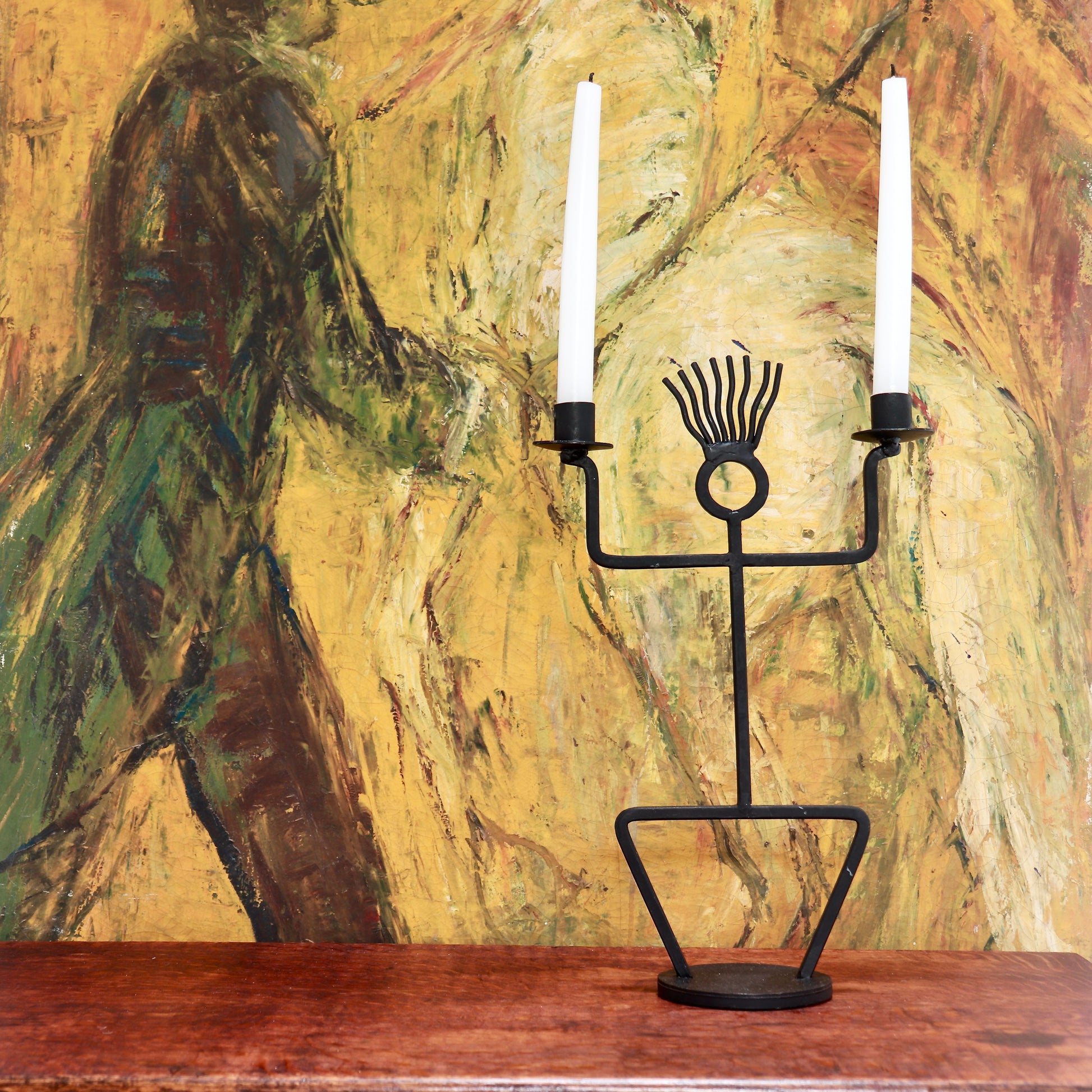 Vintage iron figure candle holder styled against artwork