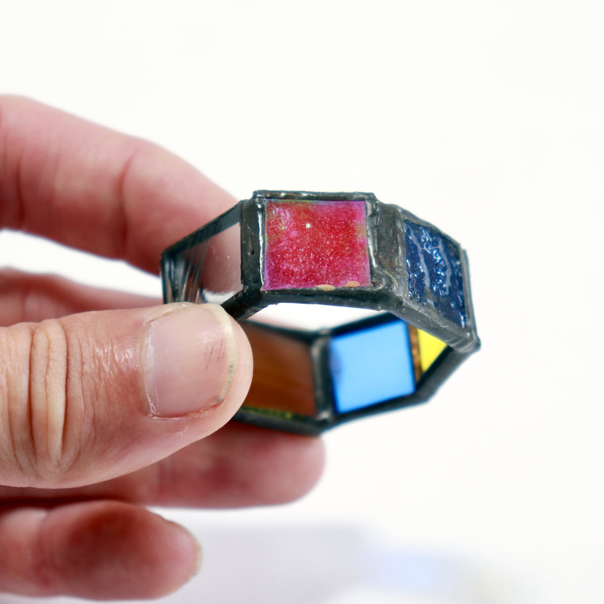 Close-up of a handmade stained glass napkin ring showing the soldered joins