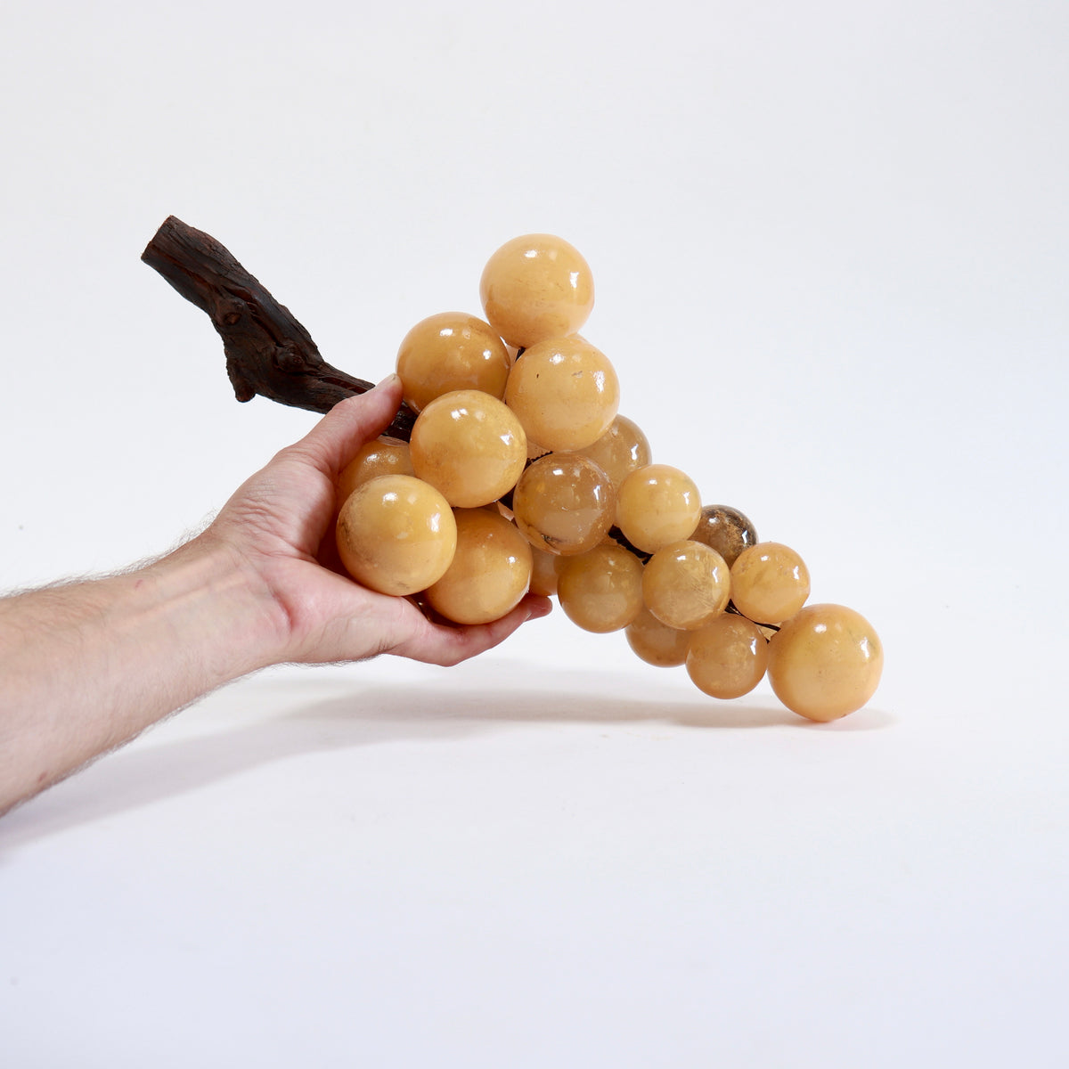 Honey-toned alabaster grape bunch supported in a hand to demonstrate its substantial size.