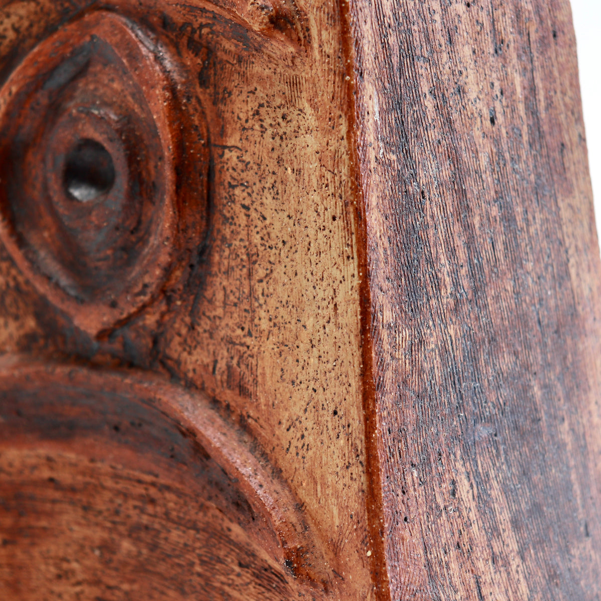 Close-up of the vessel’s ochre and russet surface, showing fine scratches, speckling and dark brown accents.