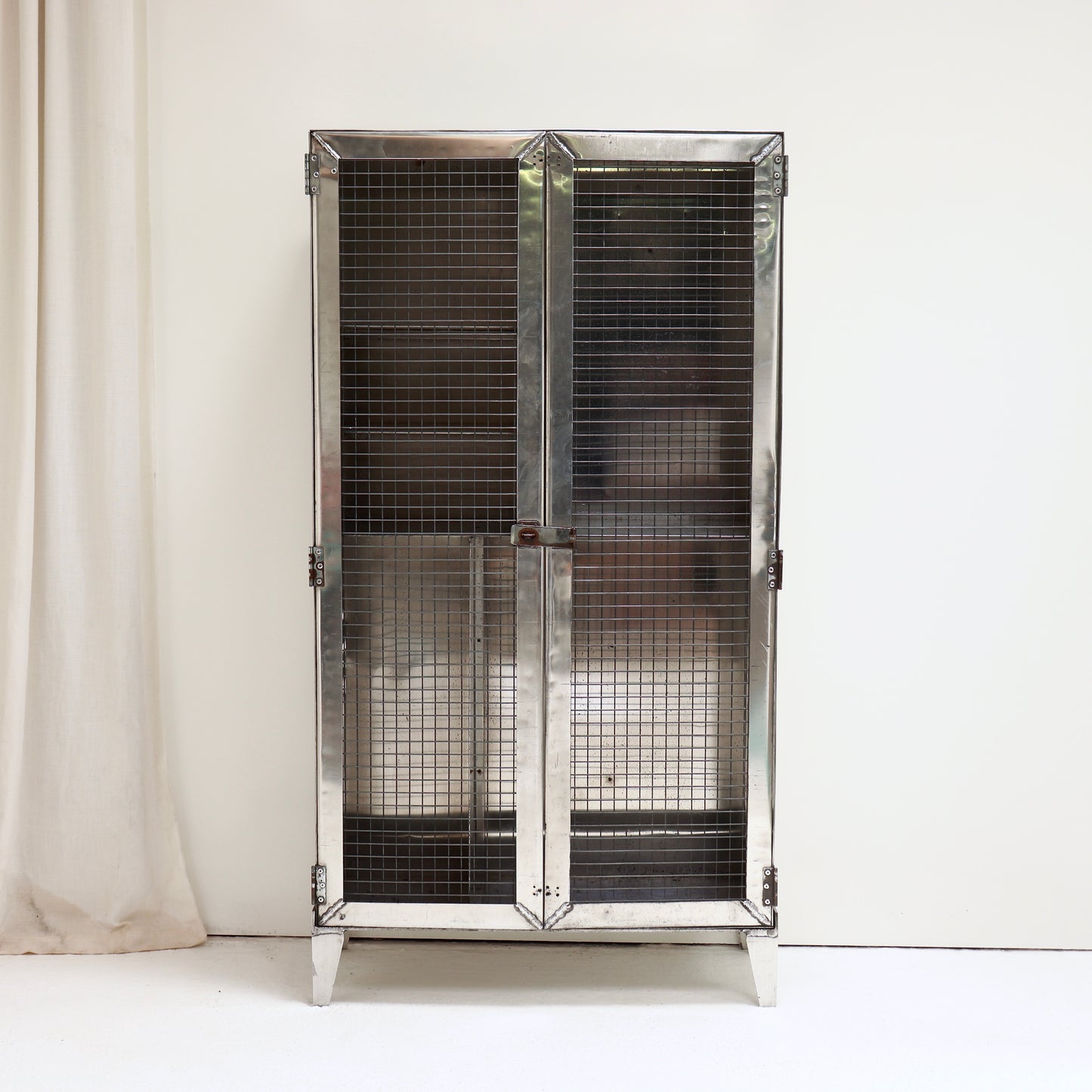 Vintage military aluminium cabinet with industrial mesh front.